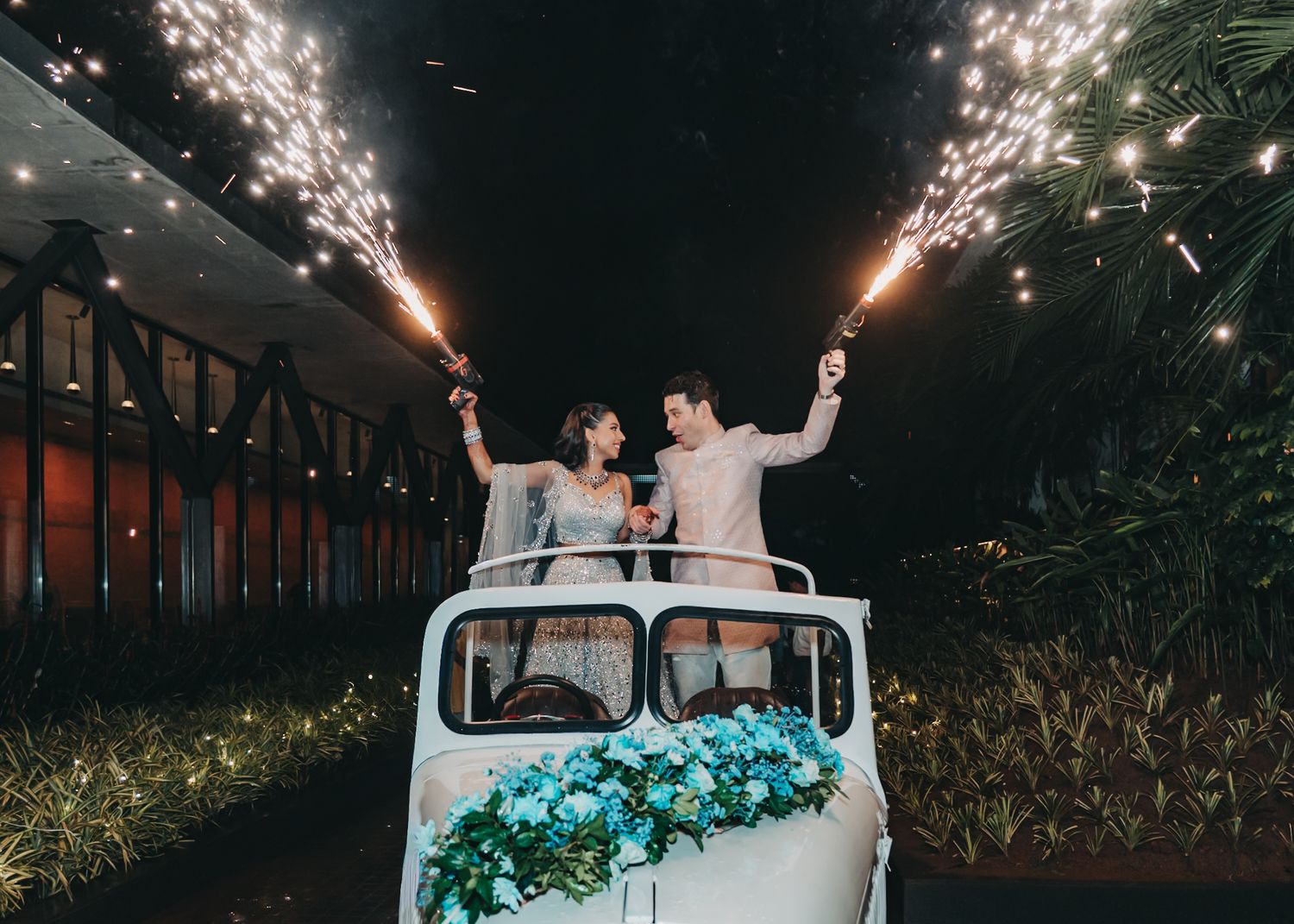 Nighttime wedding exit with sparklers and vintage white car.