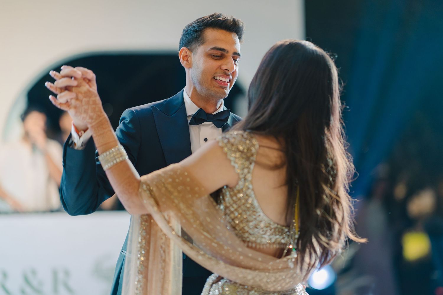 Couple dancing together at an elegant wedding reception with blue lighting.