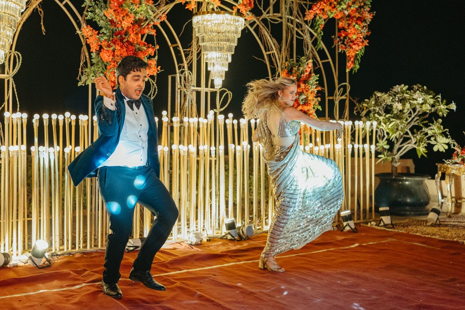 Wedding venue decorated with illuminated bamboo panels and orange floral arrangements.