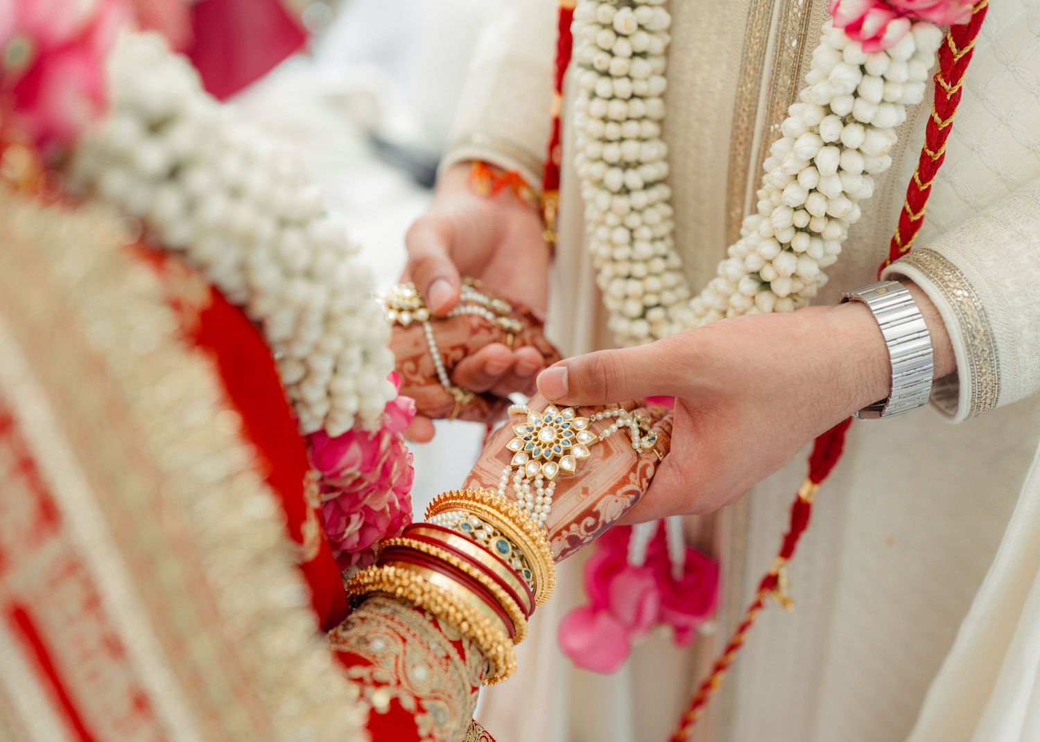 Close-up of Indian bride and groom exchanging garlands during traditional Hindu wedding ceremony with floral decorations.