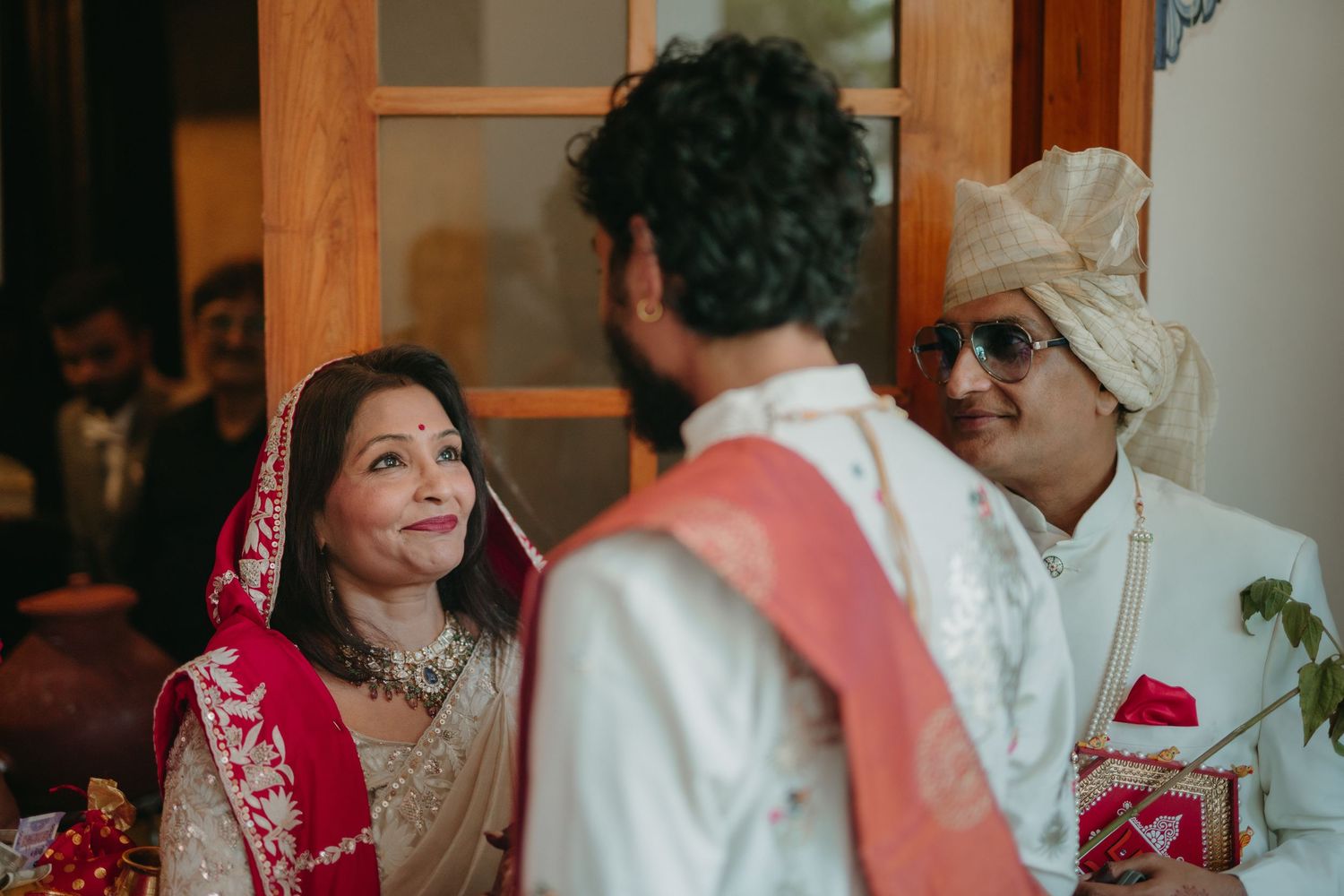 Indian bride and groom in traditional attire during wedding ceremony, wearing red dupatta and cream sherwani.