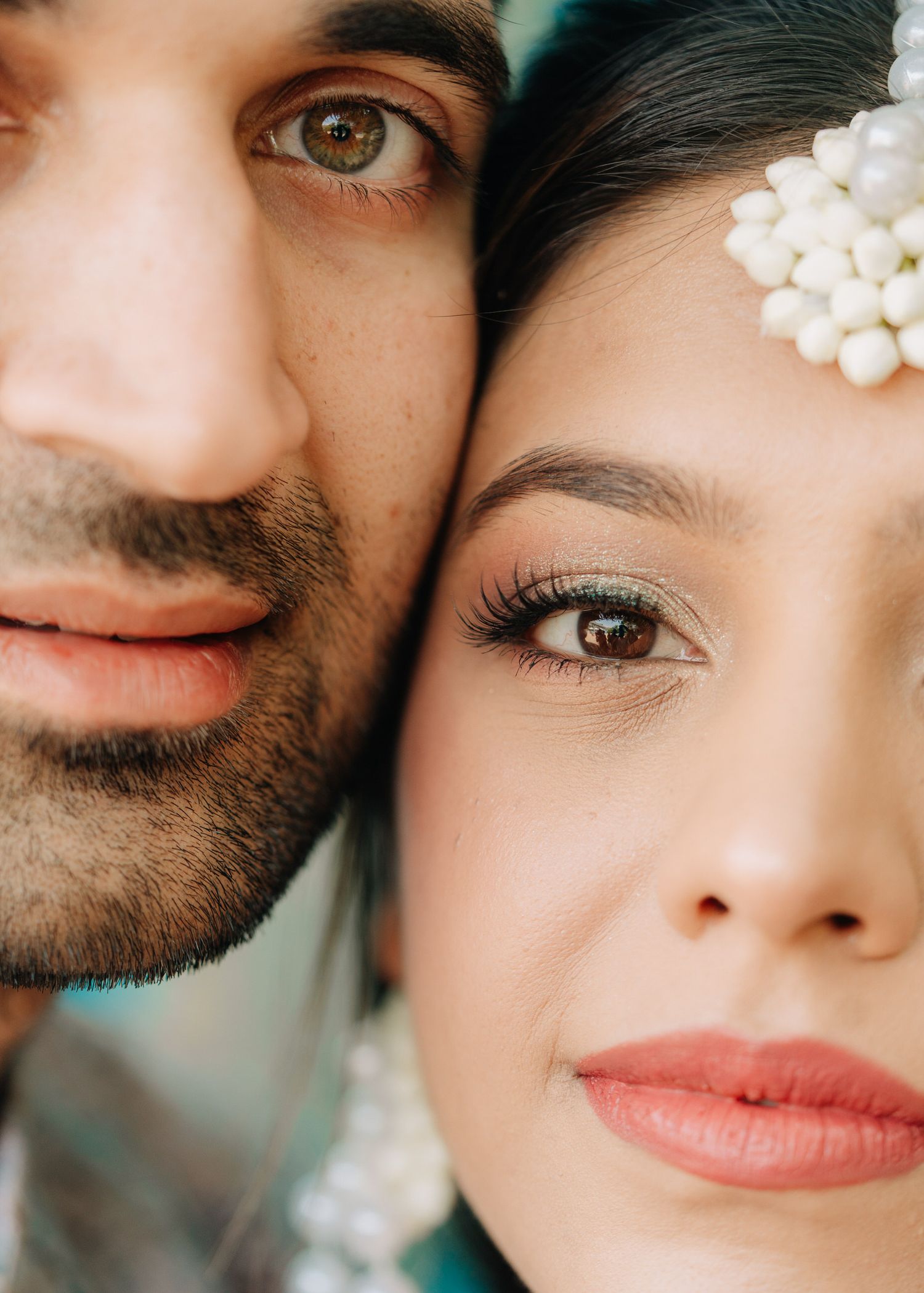 Extreme closeup of couple with pearl hair accessory and soft romantic lighting.