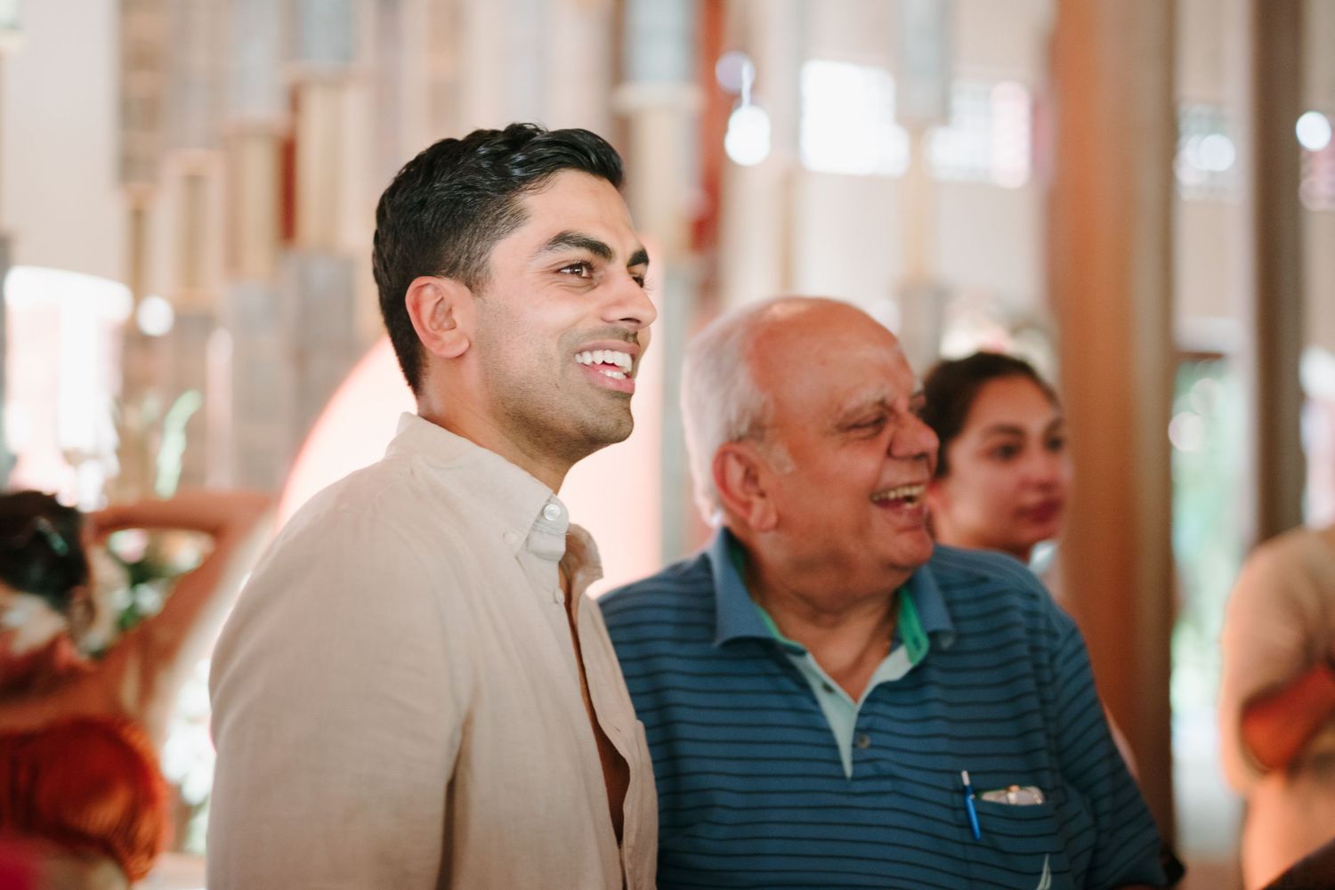 Group of people engaged in conversation during a wedding celebration at an elegant indoor venue.