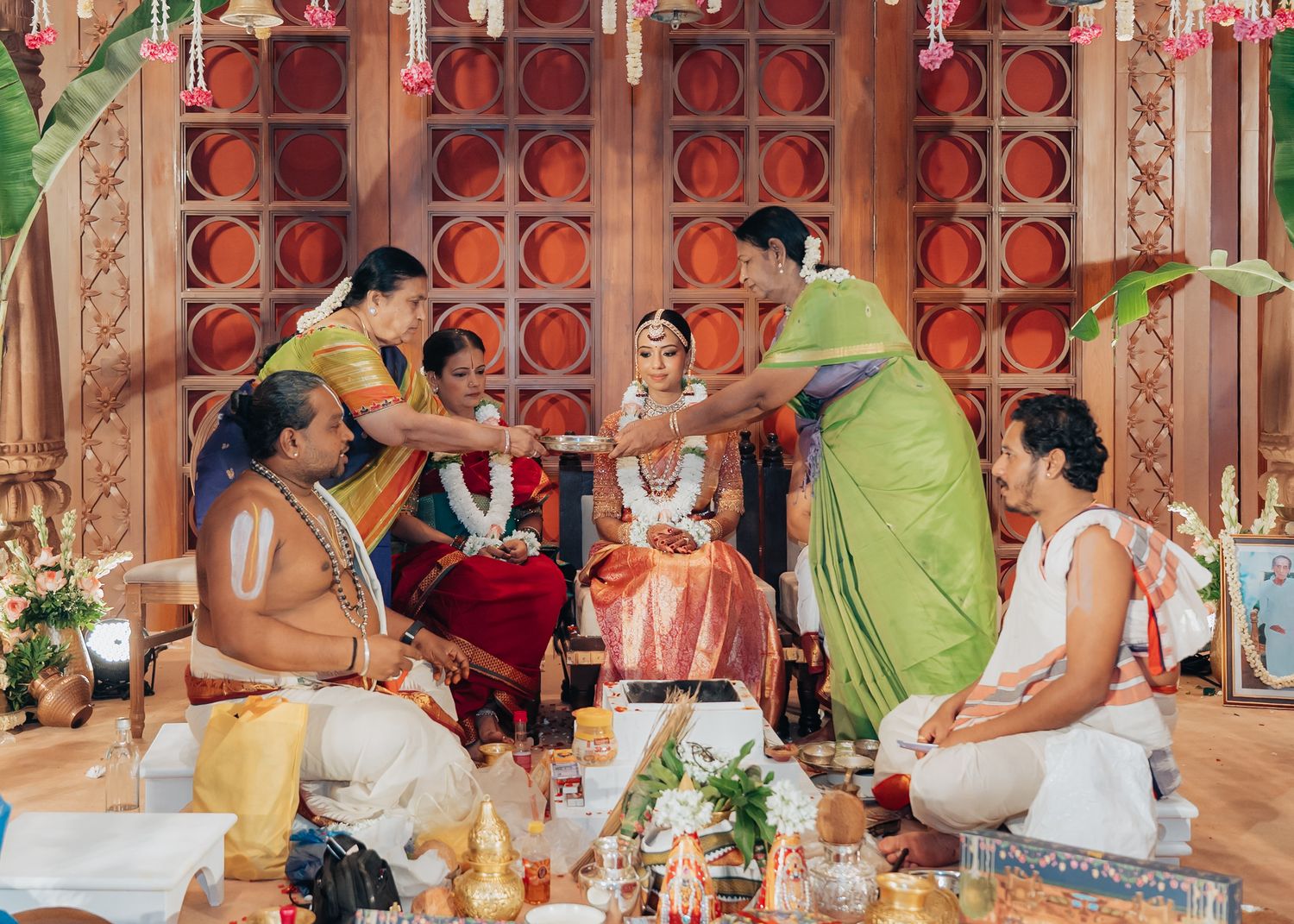 Wedding guests seated at ornate indoor reception with red decor and traditional Indian elements.