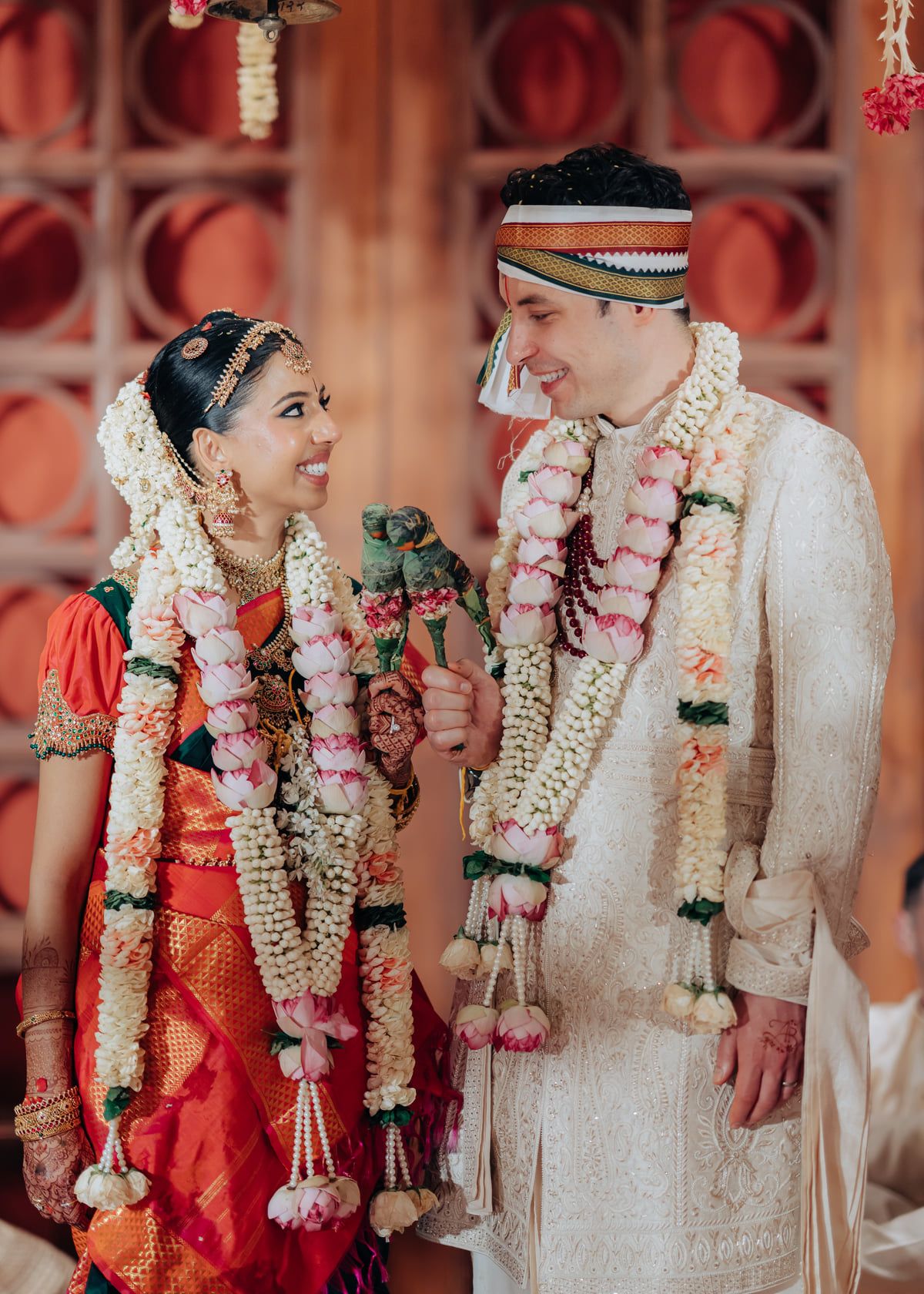 A traditional wedding ceremony with floral garlands and red sari being exchanged during a Hindu marriage ritual.