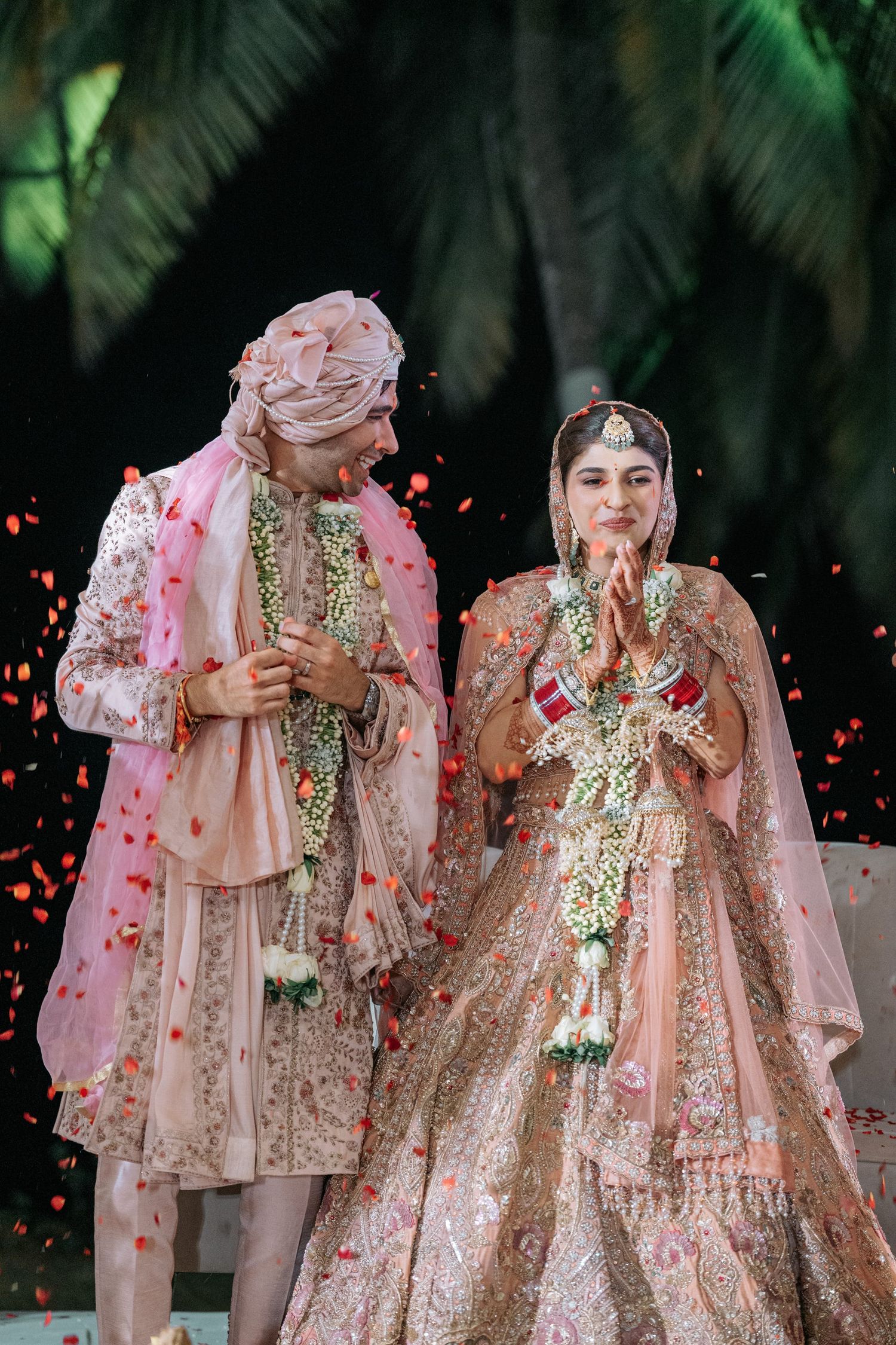 Traditional Indian wedding couple captured in a sequence of intimate moments with rose petals falling around them.