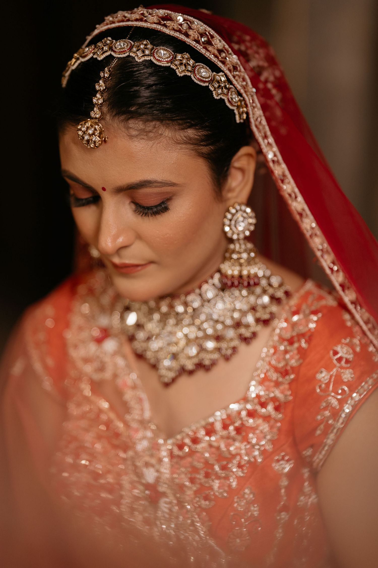 Beautiful Indian bridal portrait series showing ornate jewelry, red veil, and traditional wedding attire in warm lighting.