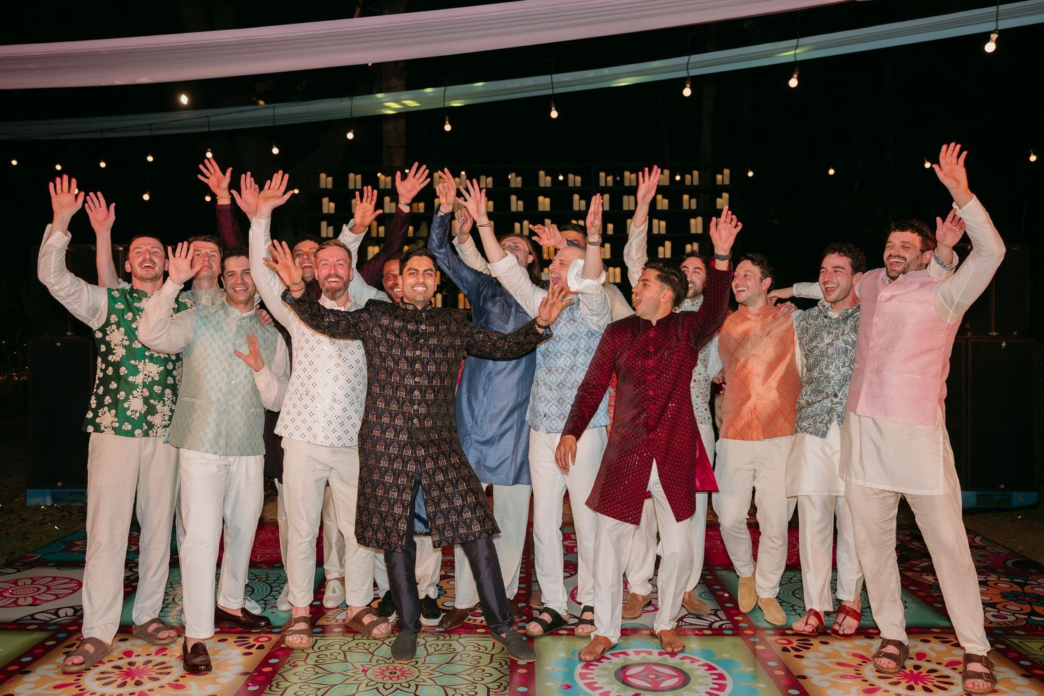 A joyful group poses with raised arms at a nighttime celebration on a decorated dance floor.