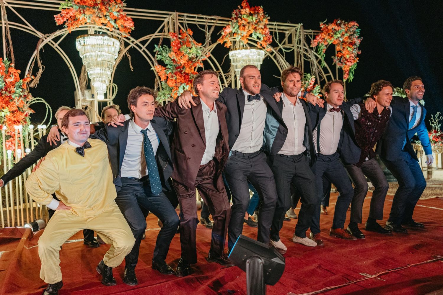 Row of formally dressed guests seated at a festive wedding reception.