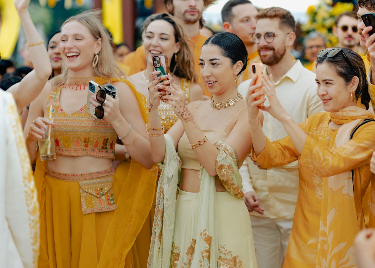 Wedding guests in coordinated yellow and gold outfits enjoying celebrations outdoors.