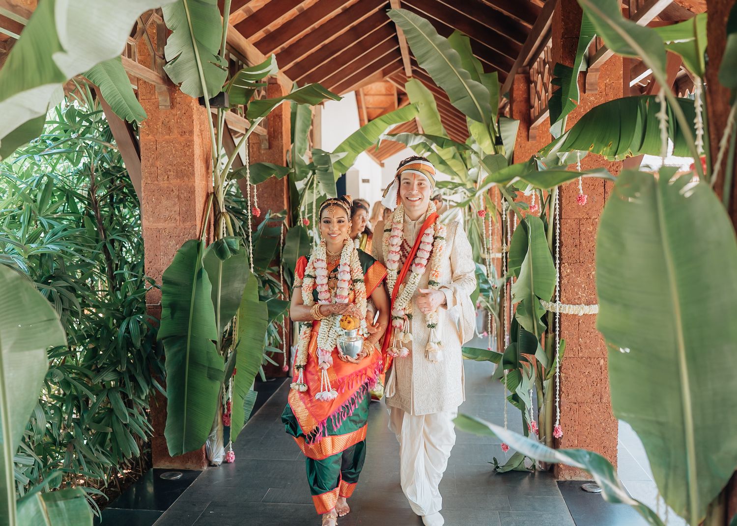 A lush outdoor wedding venue with tropical greenery and wooden beams creating a natural canopy.