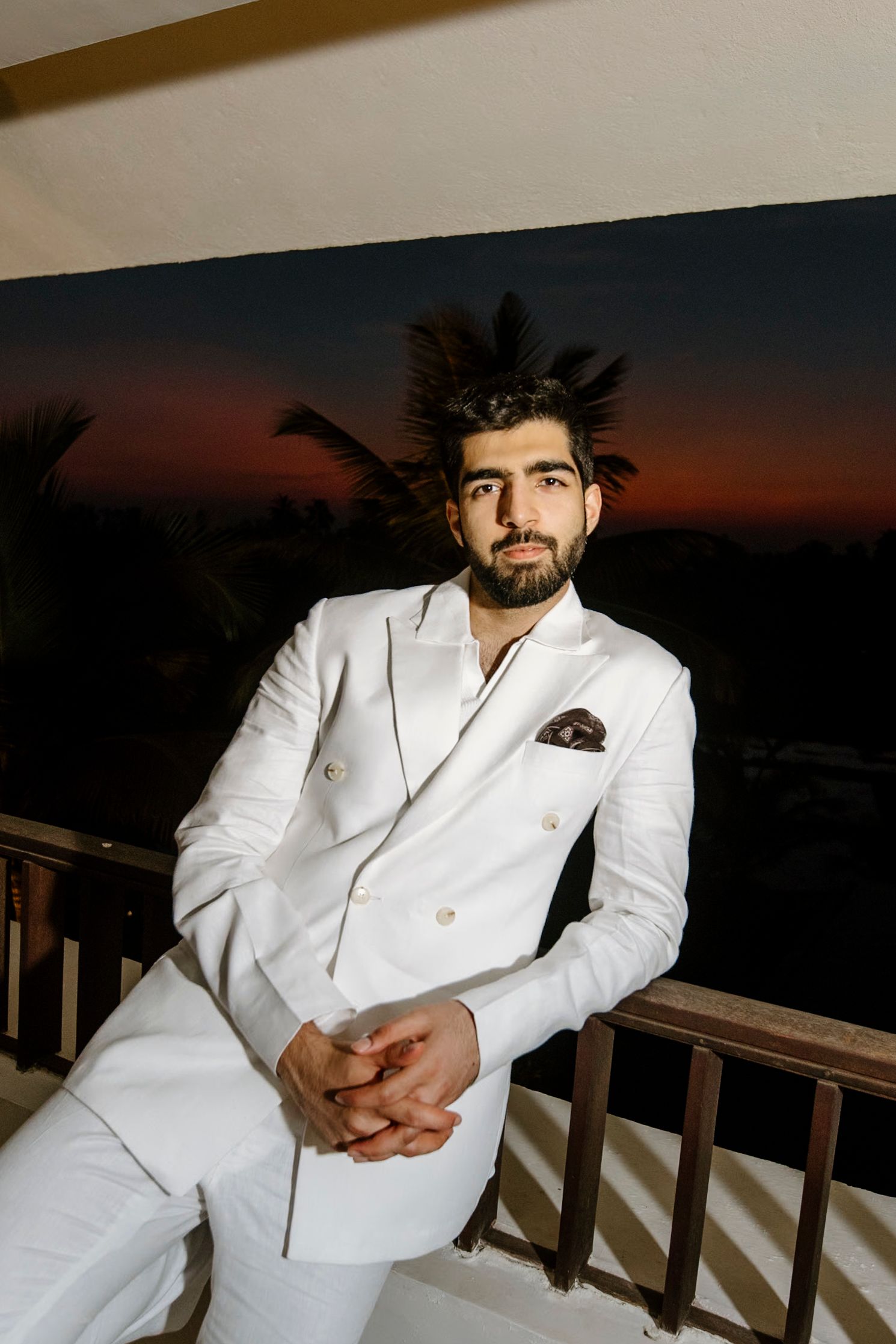 Stylish white suit portrait session against sunset sky with dramatic lighting.