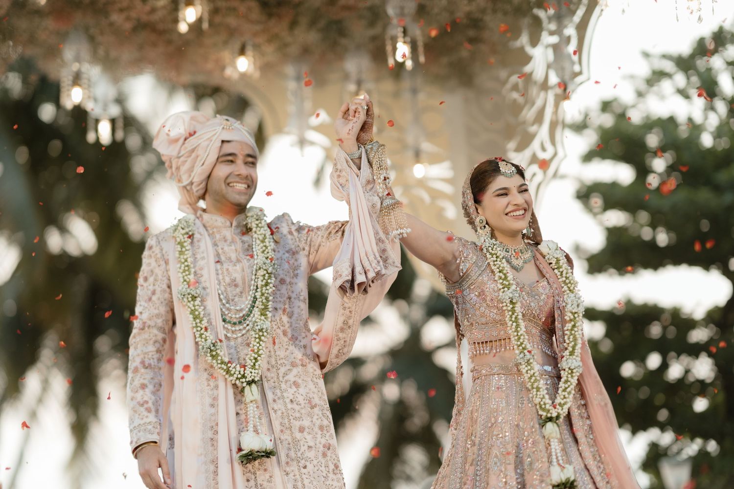 Bride and groom share joyful moments in traditional South Asian wedding attire during outdoor photo session.