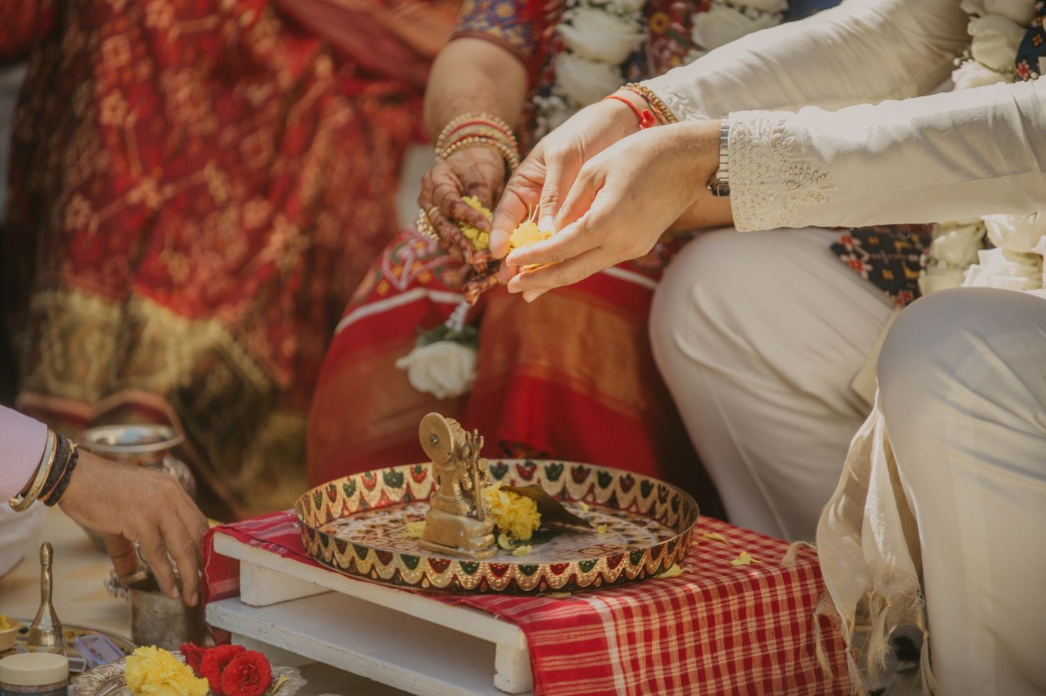 People sharing a meal at outdoor picnic with red checkered tablecloth and traditional woven basket.