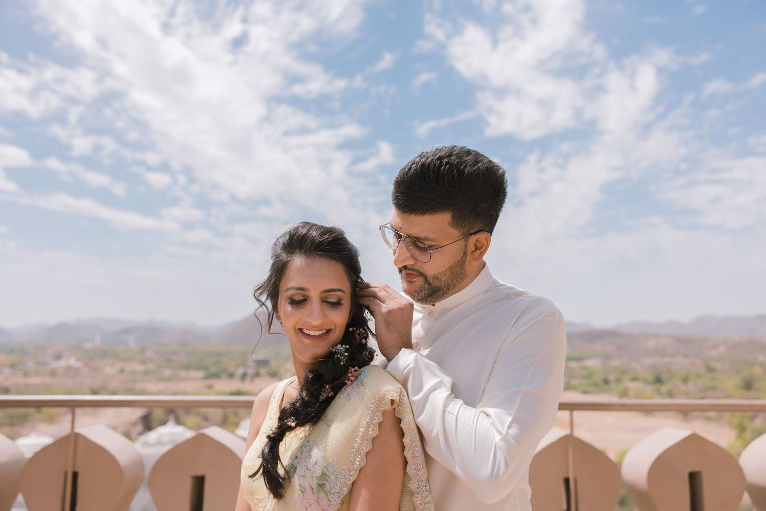 A wedding couple shares intimate moments while exploring a sun-drenched desert venue with mountain views.