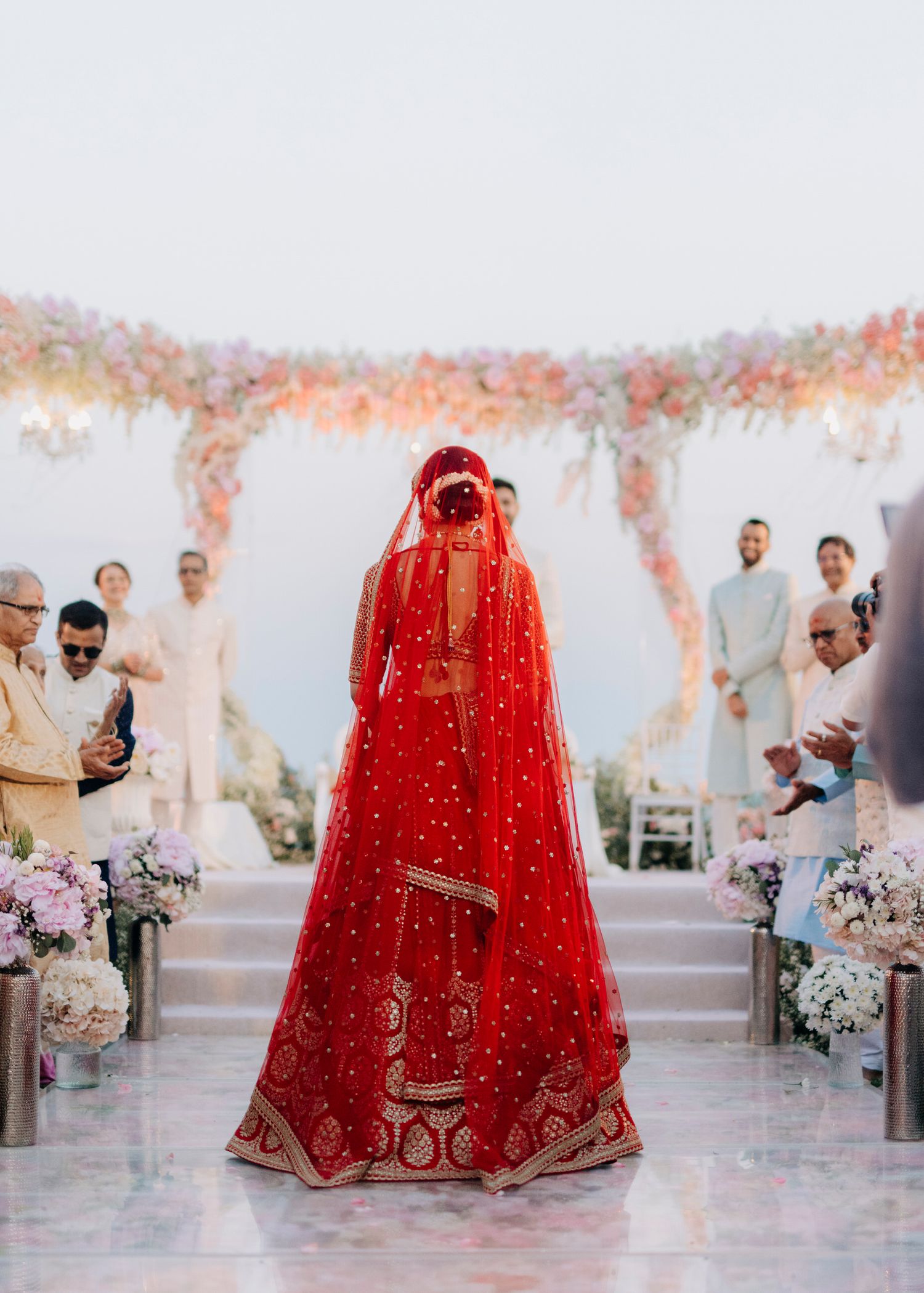 Panoramic view of a traditional South Asian wedding ceremony with red decor and white floral arrangements.