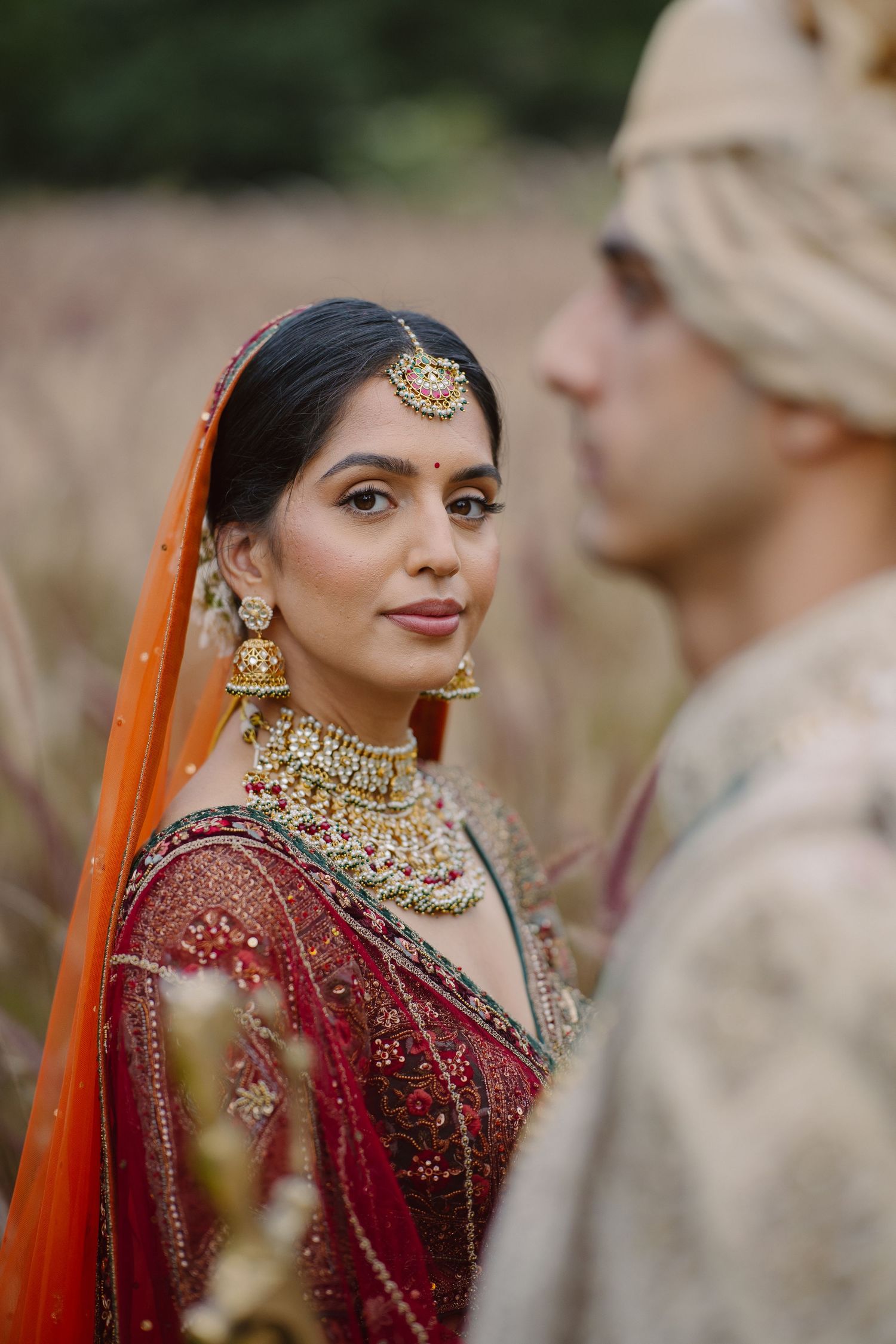 Traditional Indian wedding ceremony with ornate red and gold bridal attire and elegant floral decor.