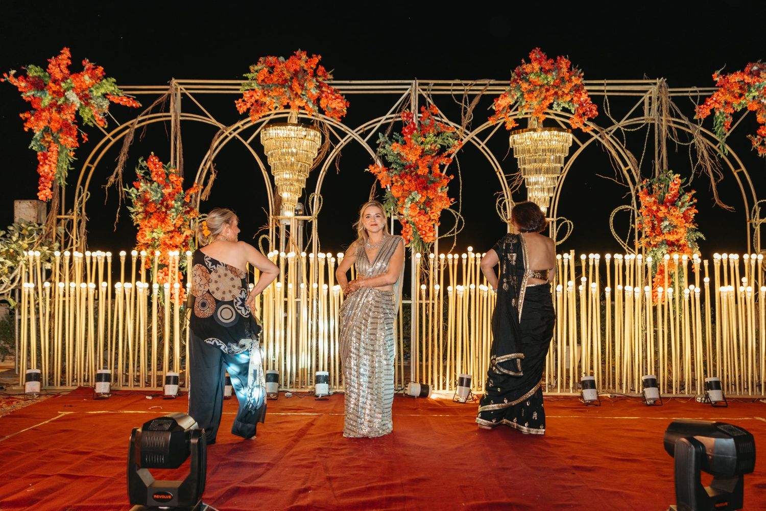 Elegant wedding arch decorated with orange flowers and golden accents for an evening ceremony.