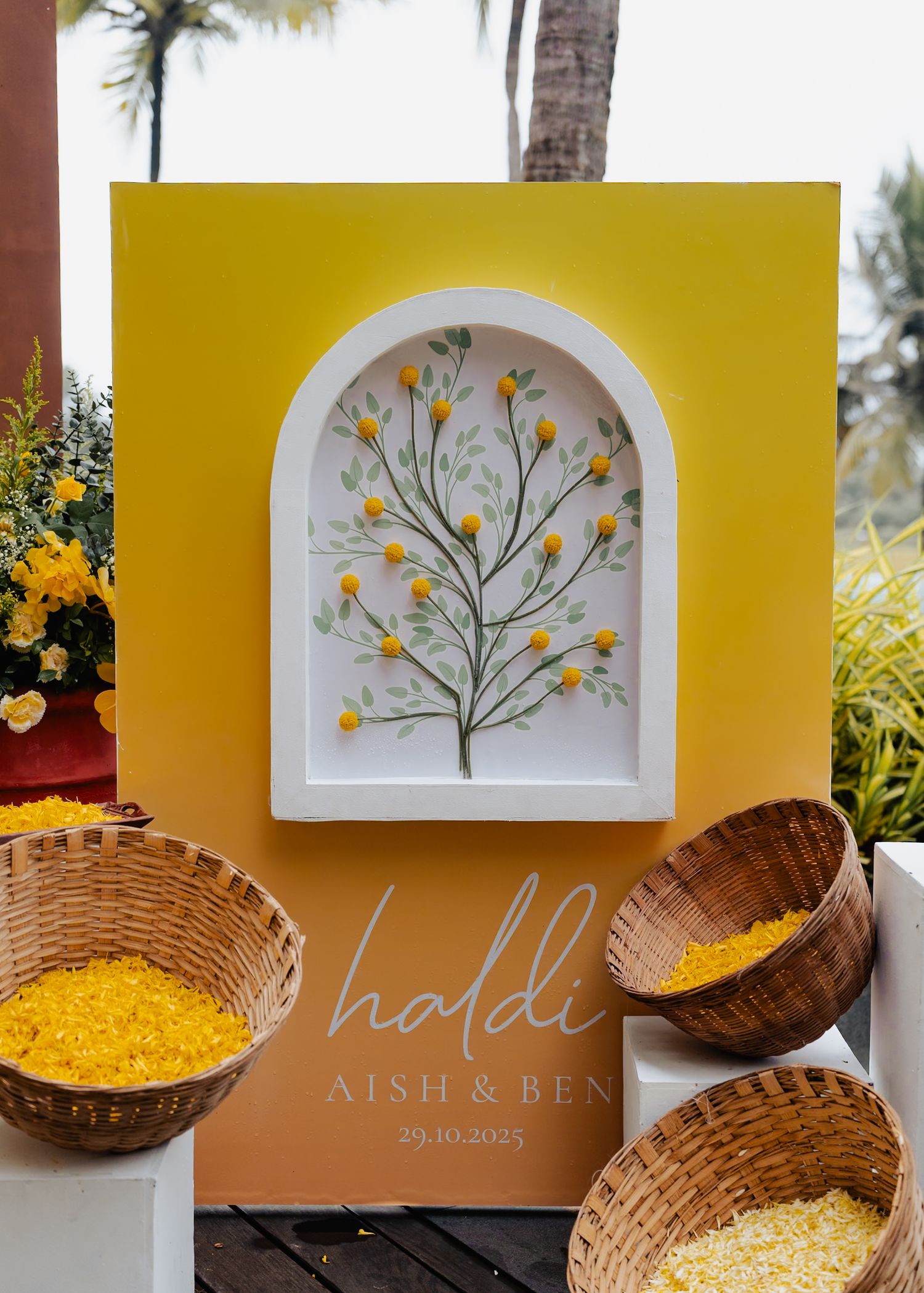 Yellow floral art installation with tree design in white archway alongside decorative woven baskets.