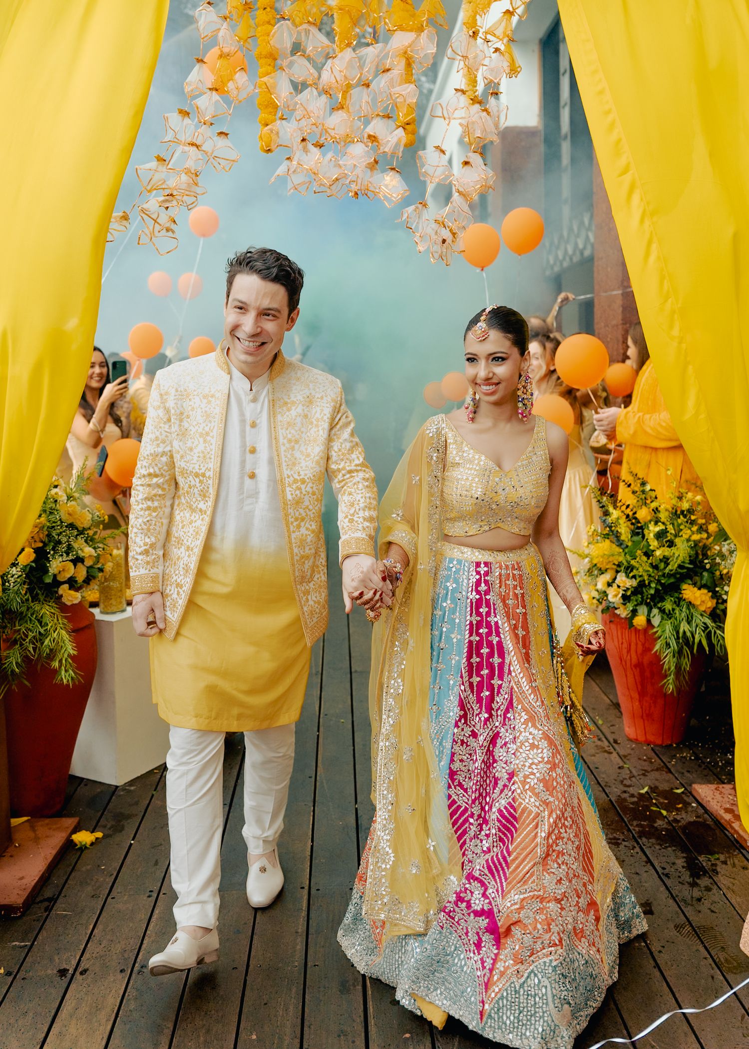 Wedding celebration with yellow drapes and floral decorations featuring a couple in traditional Indian attire.