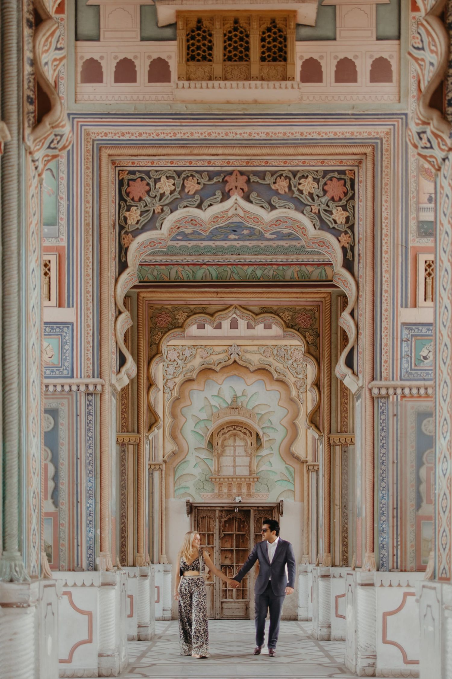 A long ornate palace corridor with intricate painted details and arched doorways.