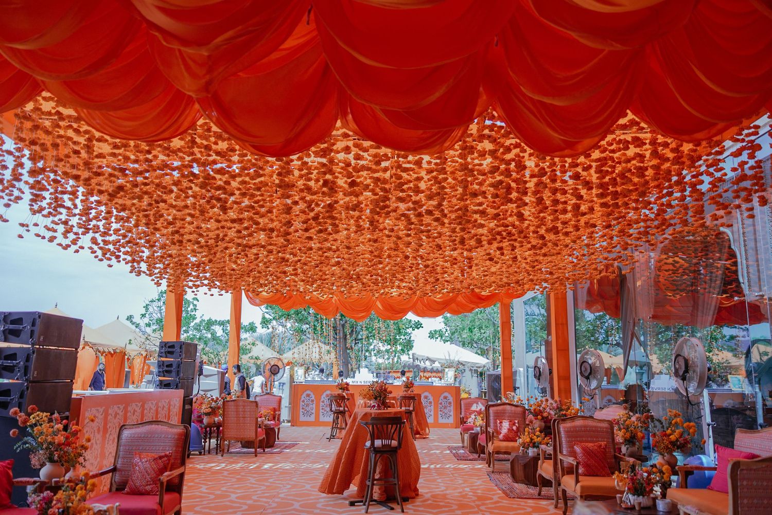 Red fabric canopies stretch across a bustling outdoor market creating a vibrant orange-tinted atmosphere.