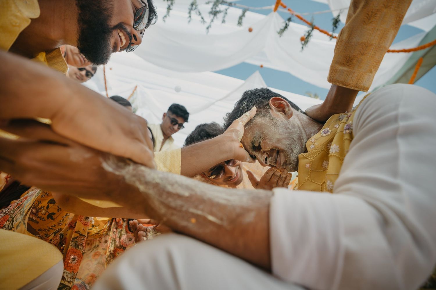 Traditional ritual ceremony with participants seated closely together during a cultural gathering in bright lighting.