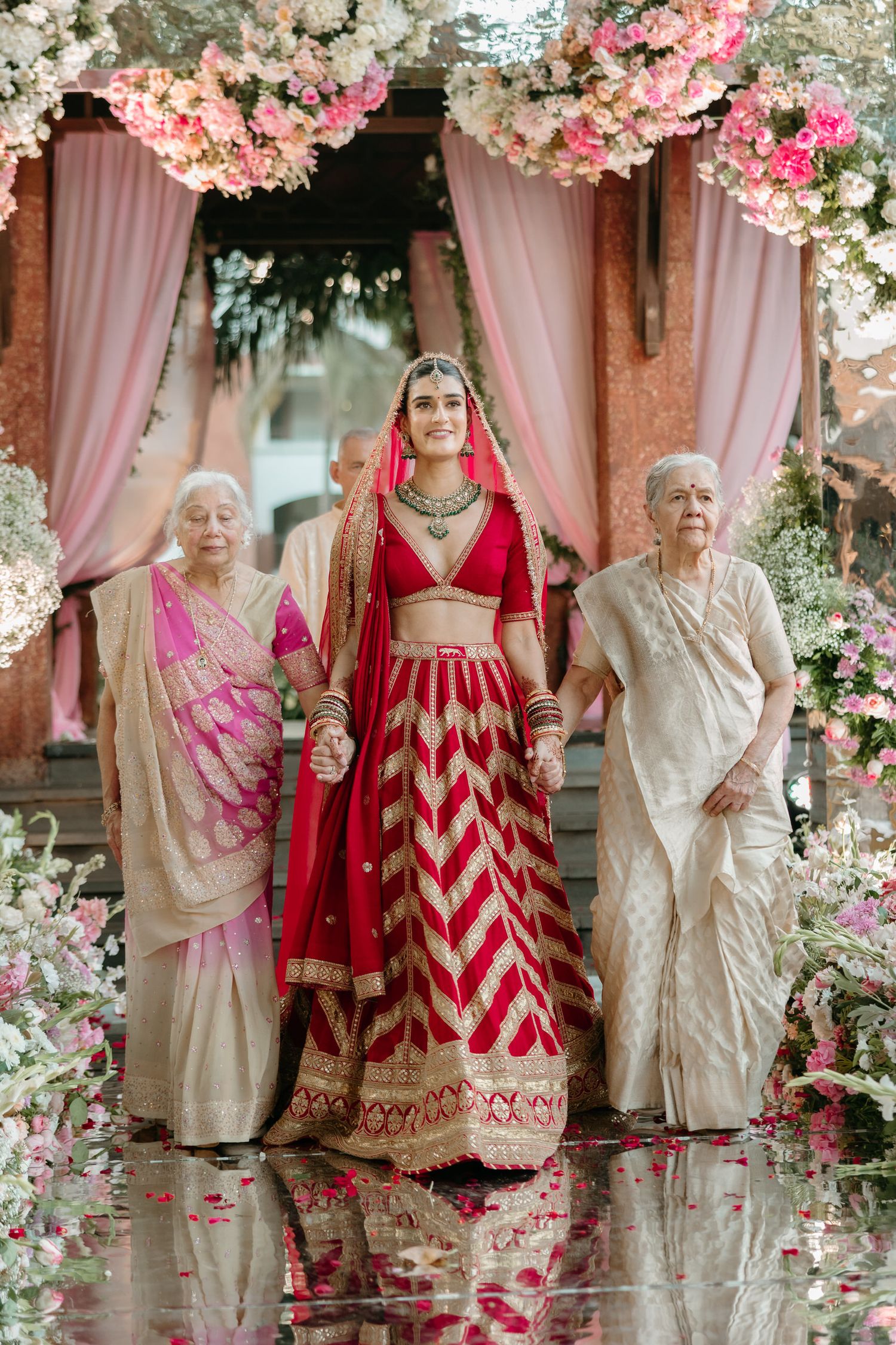 A traditional Indian wedding ceremony decorated with pink cherry blossoms and elegant pink drapery.