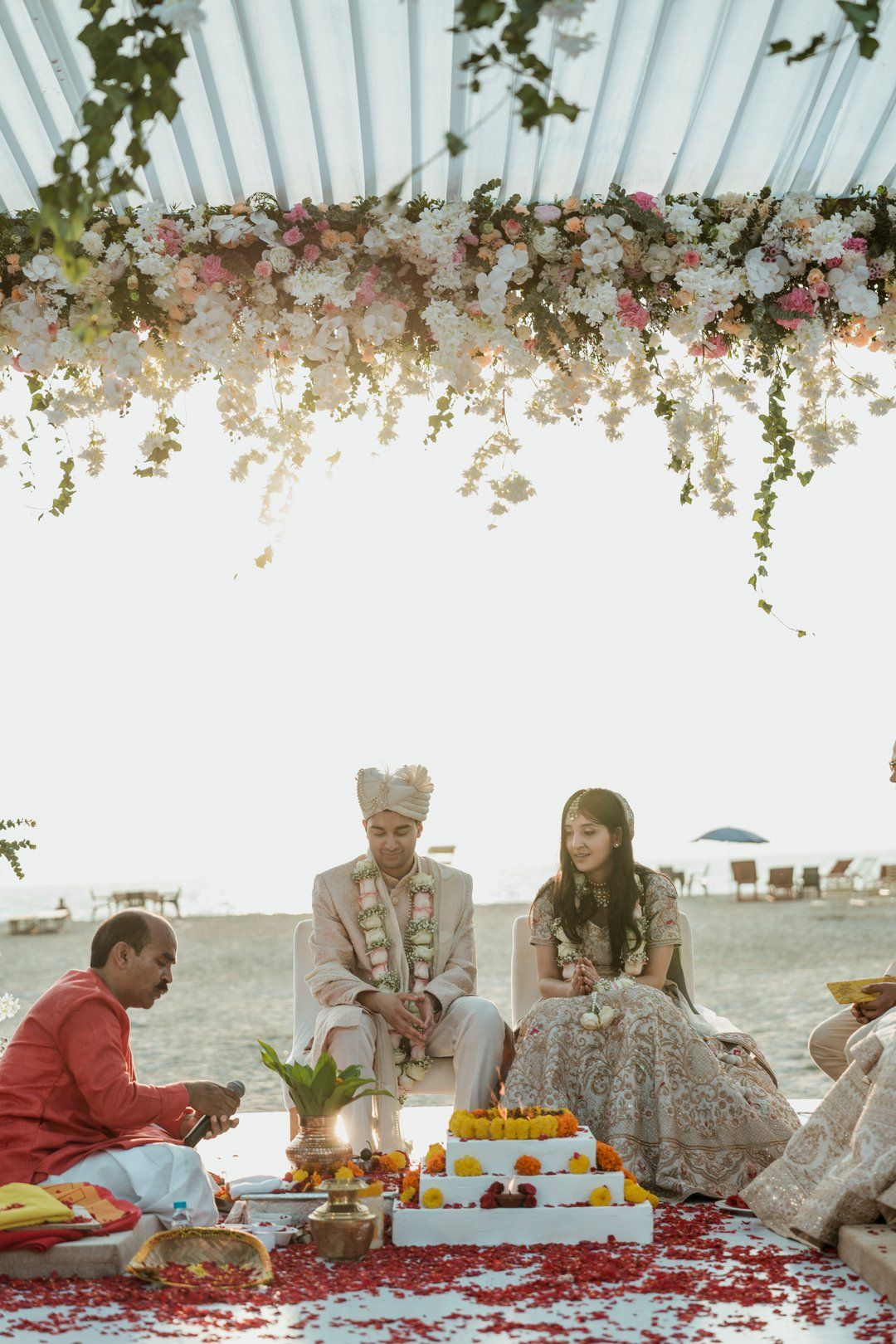 Elegant outdoor dining setup with floral ceiling decorations and ocean views.