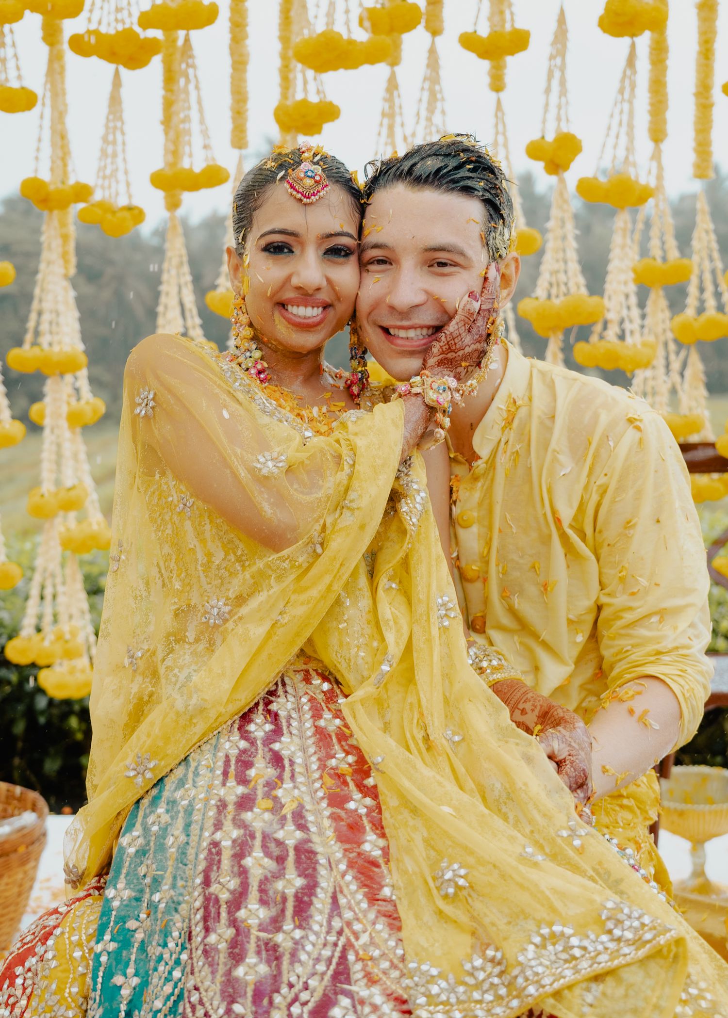 Traditional Haldi ceremony celebration with yellow decorations and marigold garlands hanging overhead.