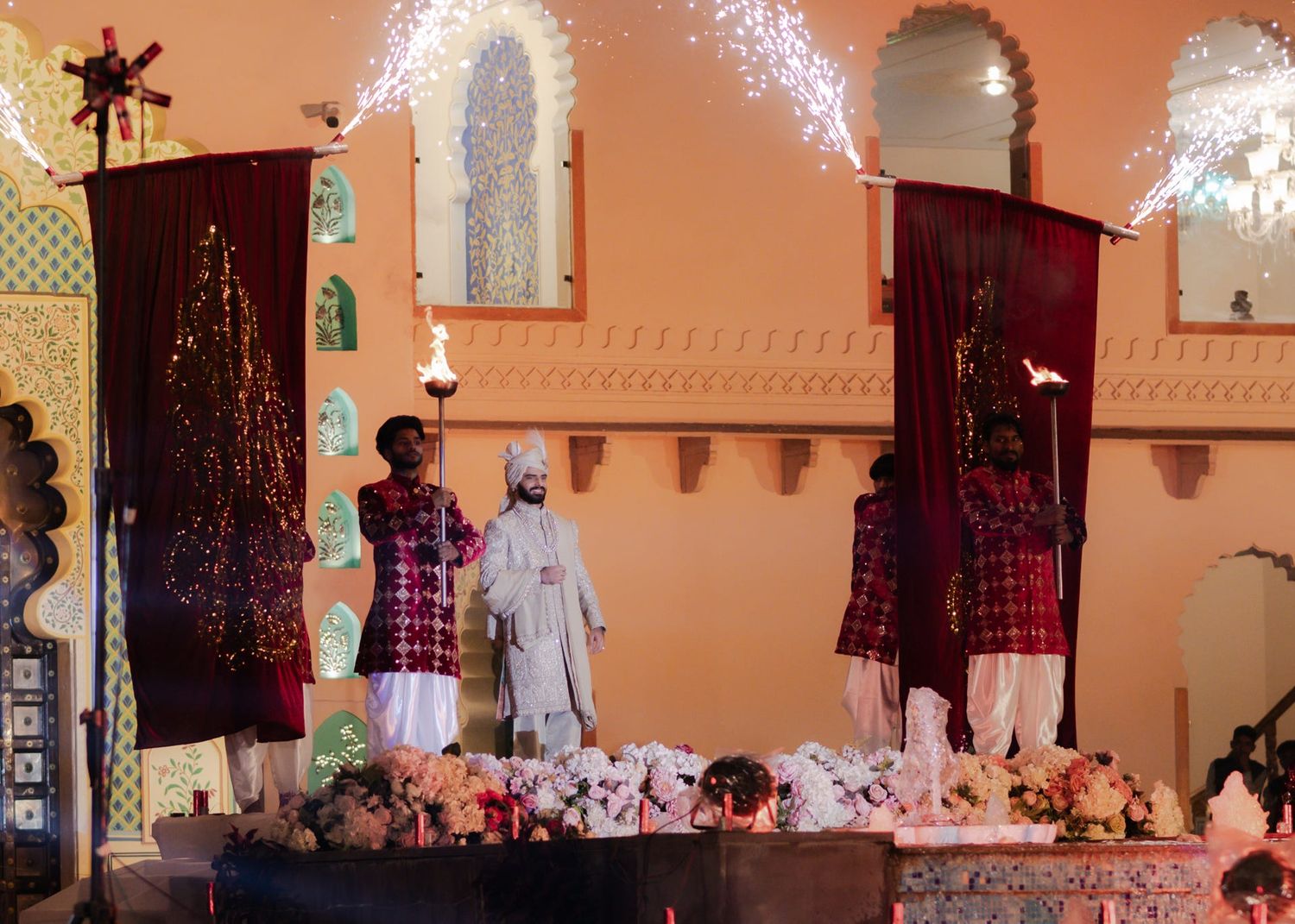 Colorful cultural ceremony with traditionally dressed performers standing before a decorated altar with sparkling lights.