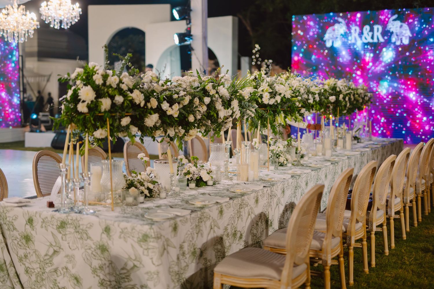 Luxurious wedding reception hall decorated with crystal chandeliers and elegant white table settings.