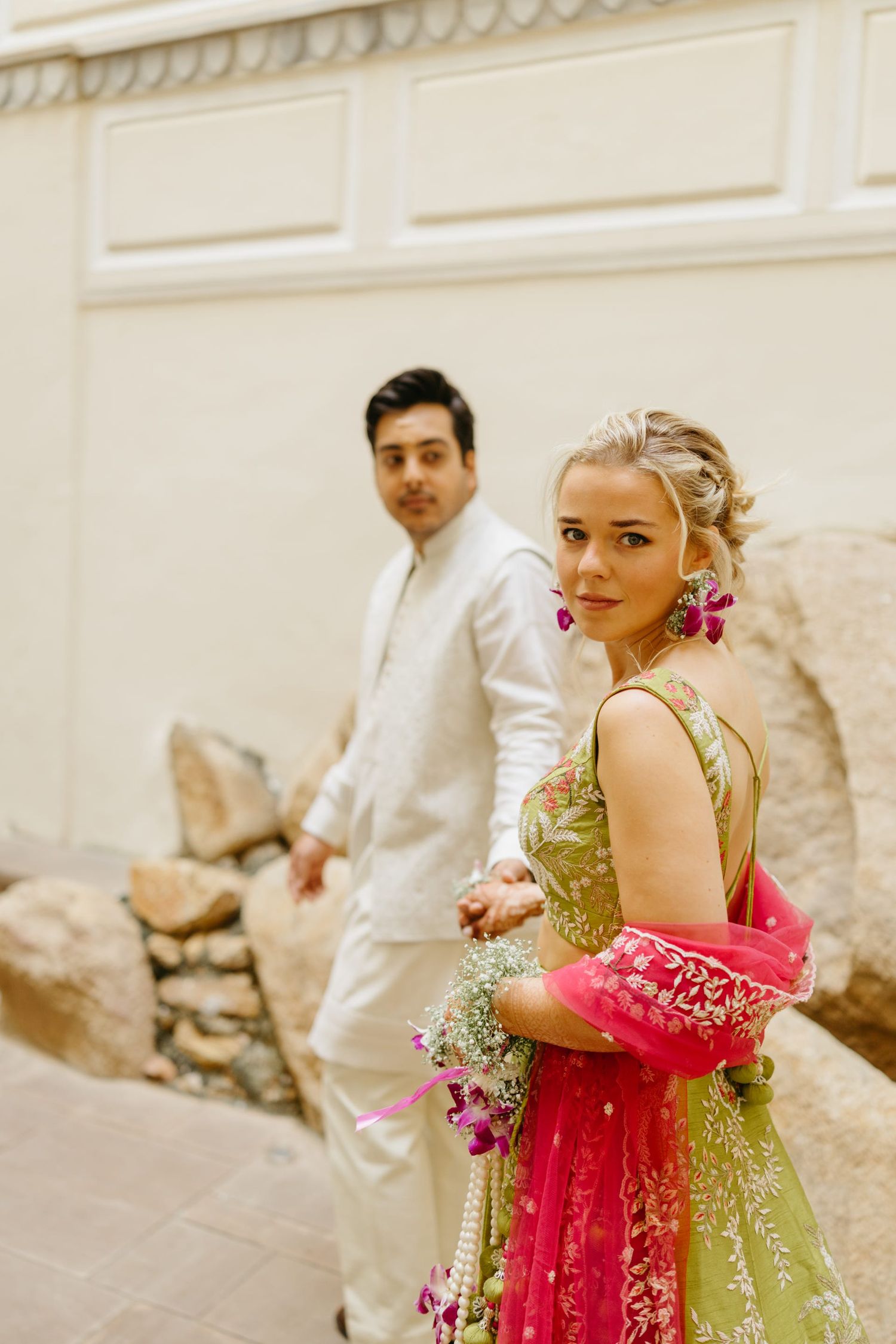 A playful couple in traditional Indian fusion wear share moments on white marble steps.