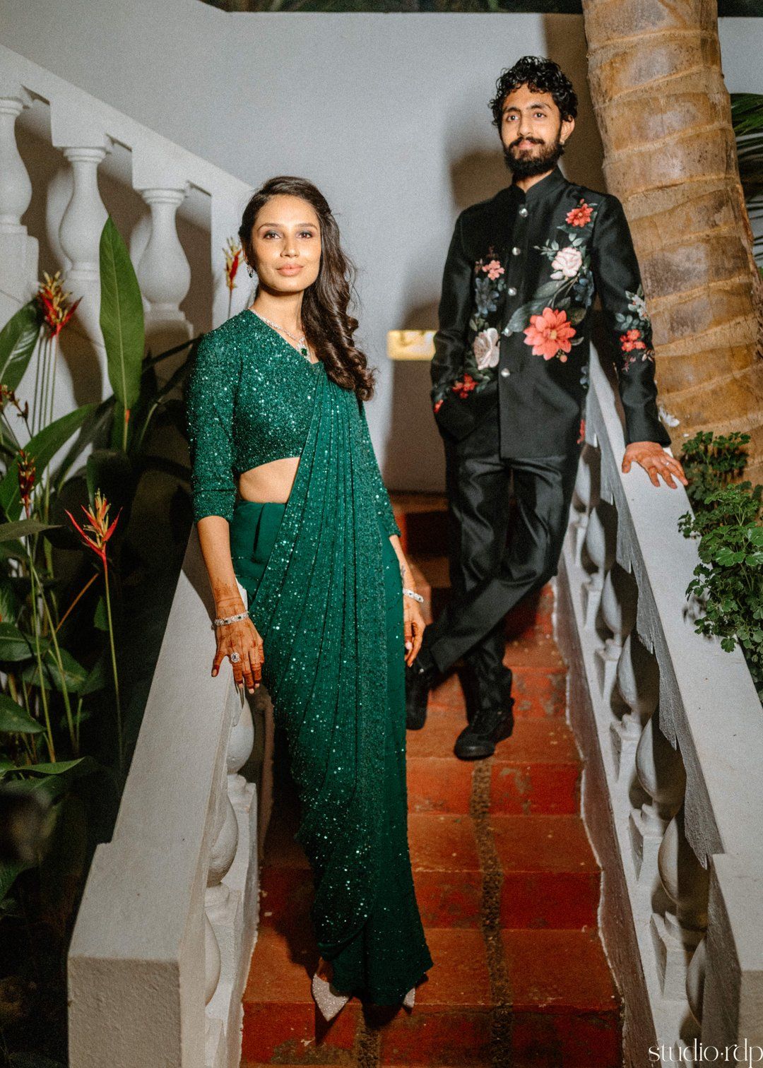 Romantic evening photoshoot on brick steps with couple in sparkly green and floral black formal wear.