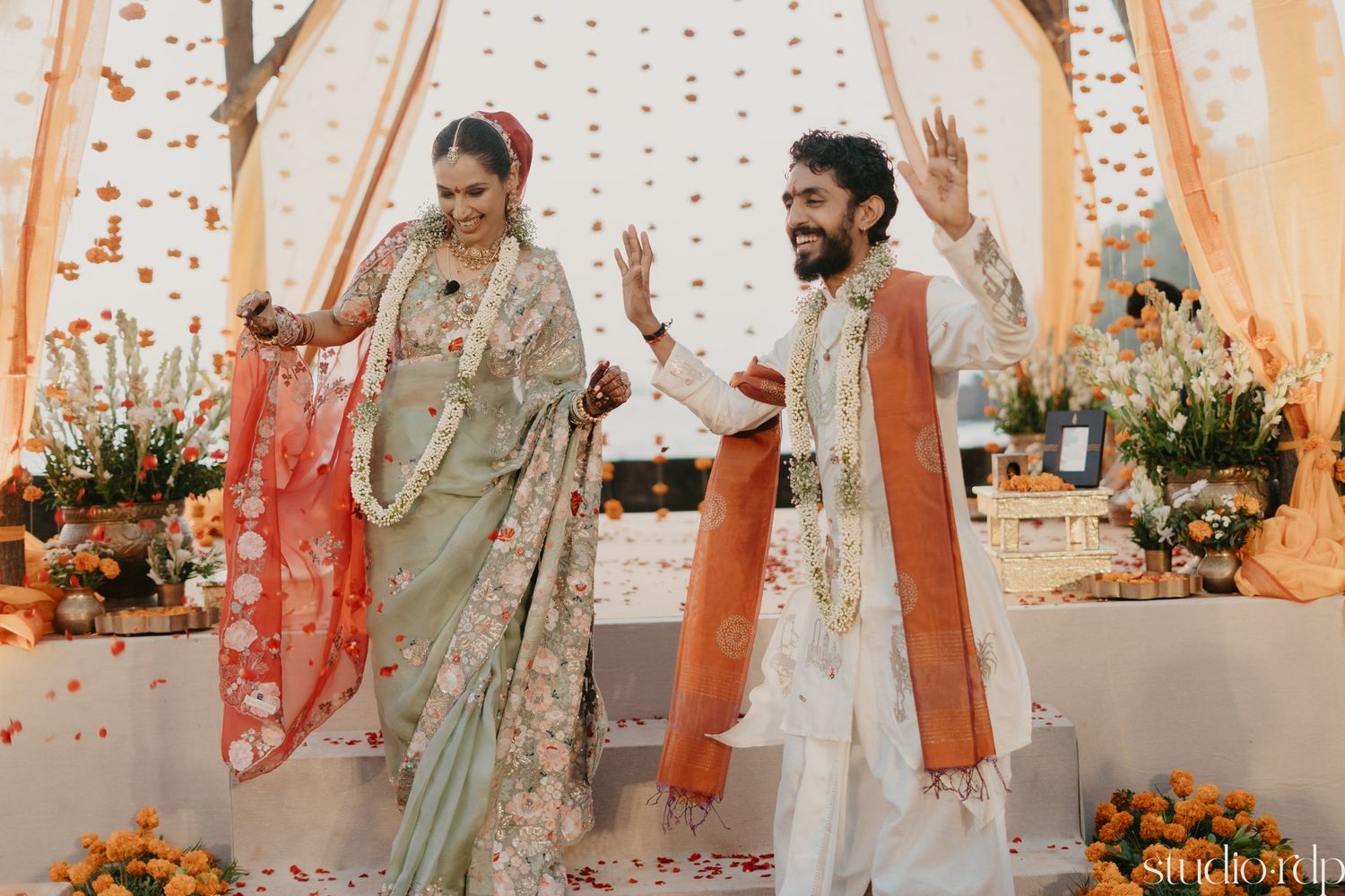 Traditional Indian wedding ceremony with ornate decor and floral arrangements under a draped mandap.