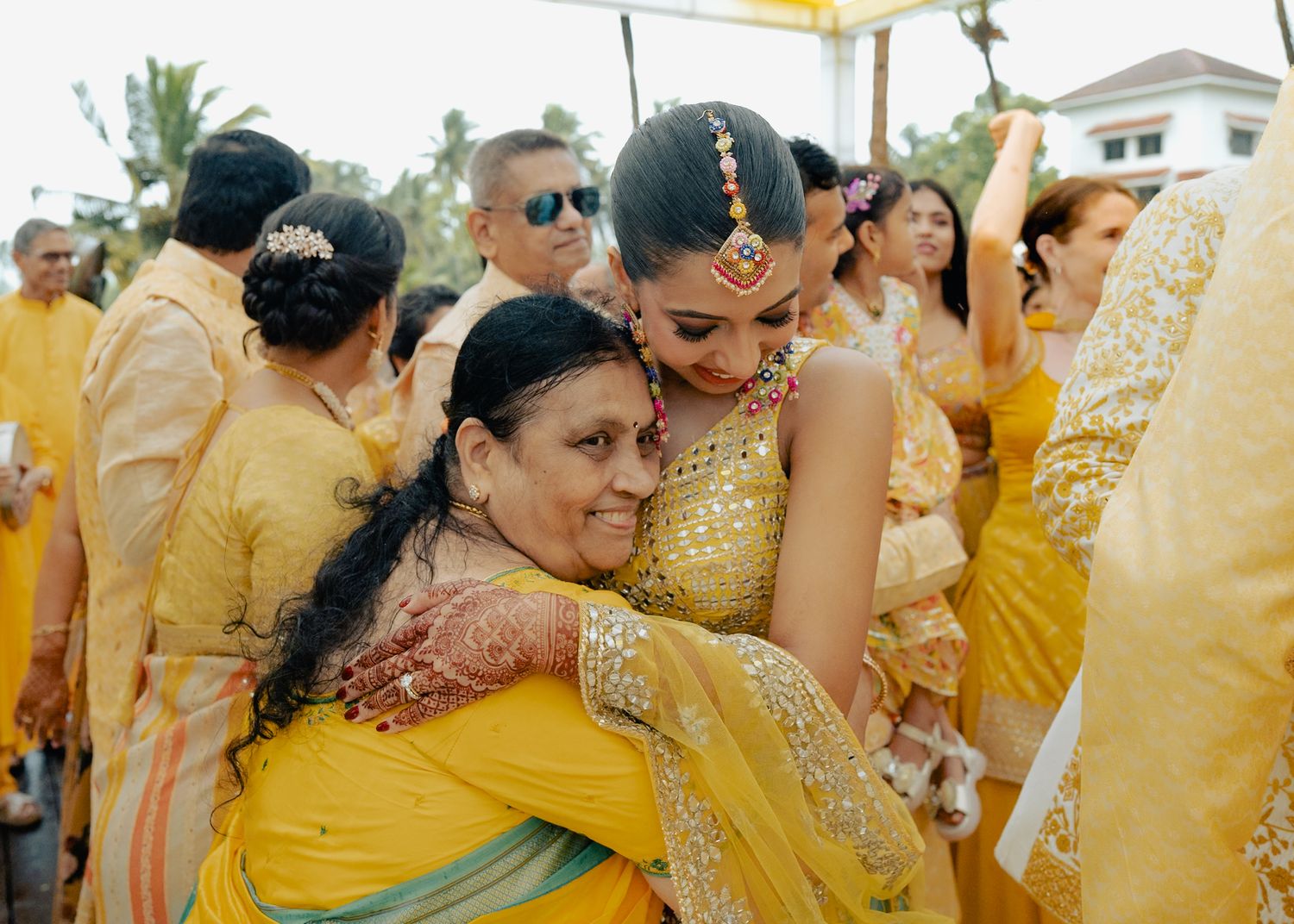 Festive wedding party in yellow and gold traditional Indian clothing celebrating outdoors.
