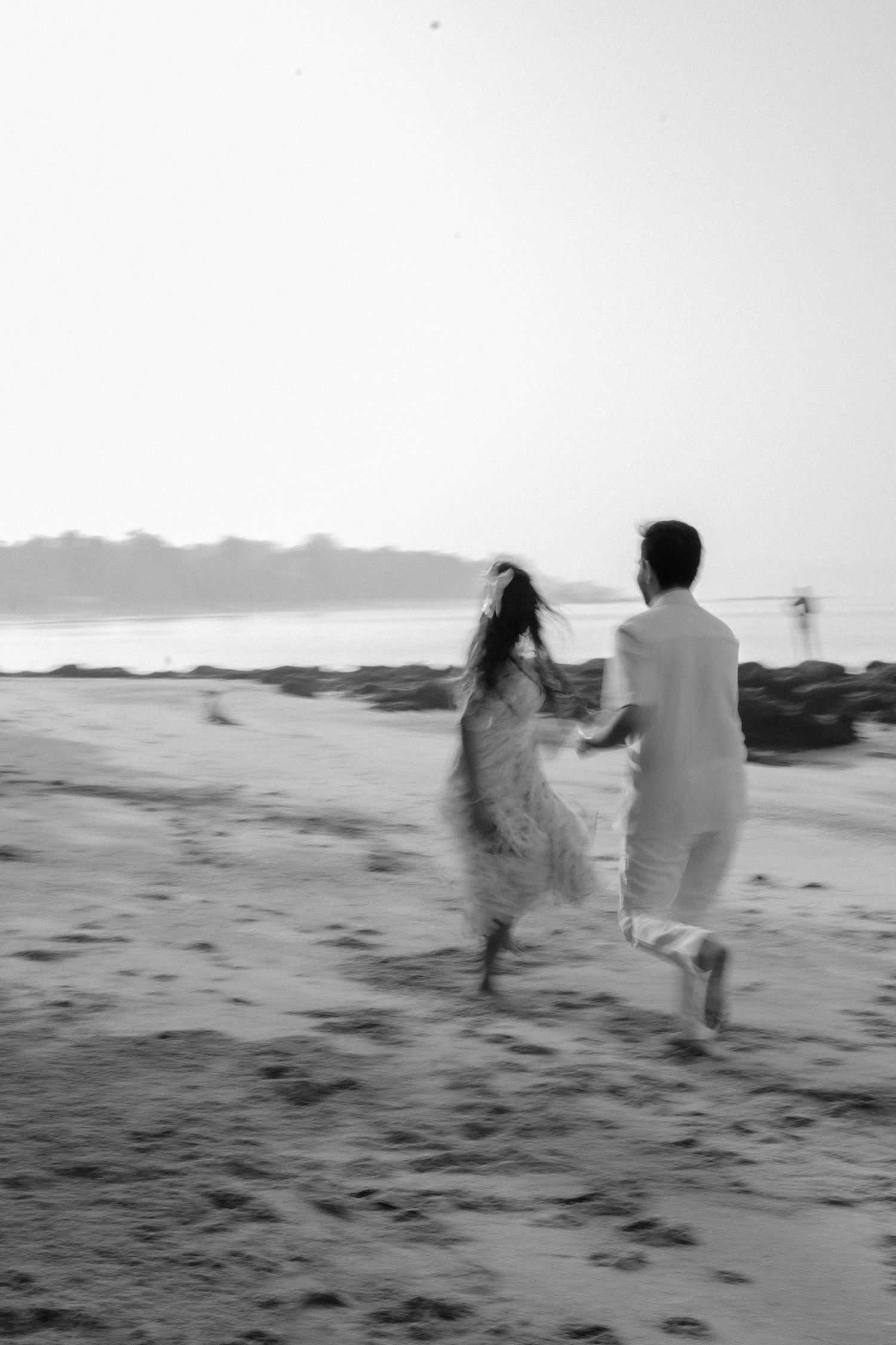 Black and white silhouette of a playful couple running along a misty Goa beach during a pre wedding shoot by Studio RDP