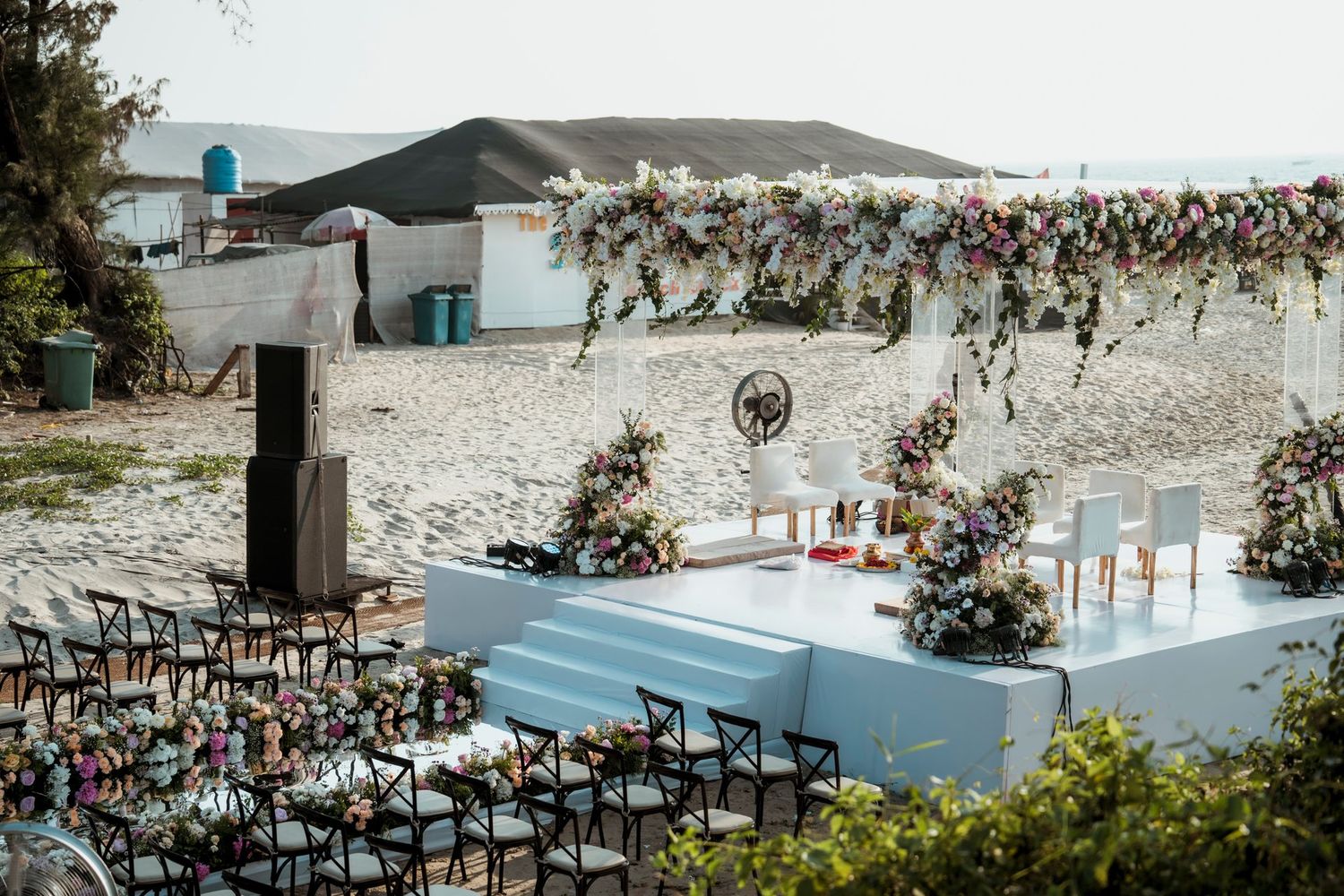 Modern beach wedding venue setup with rows of chairs and white decor elements.