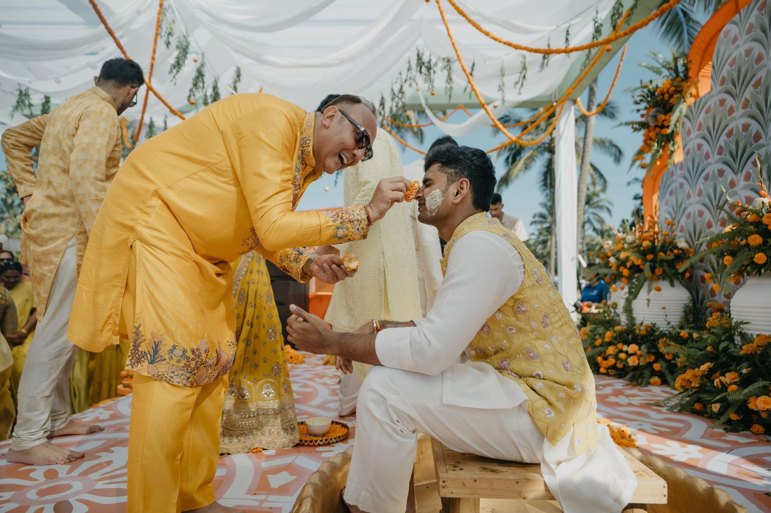 Wedding party wearing yellow traditional attire performs ceremony rituals in a beautifully decorated setting.