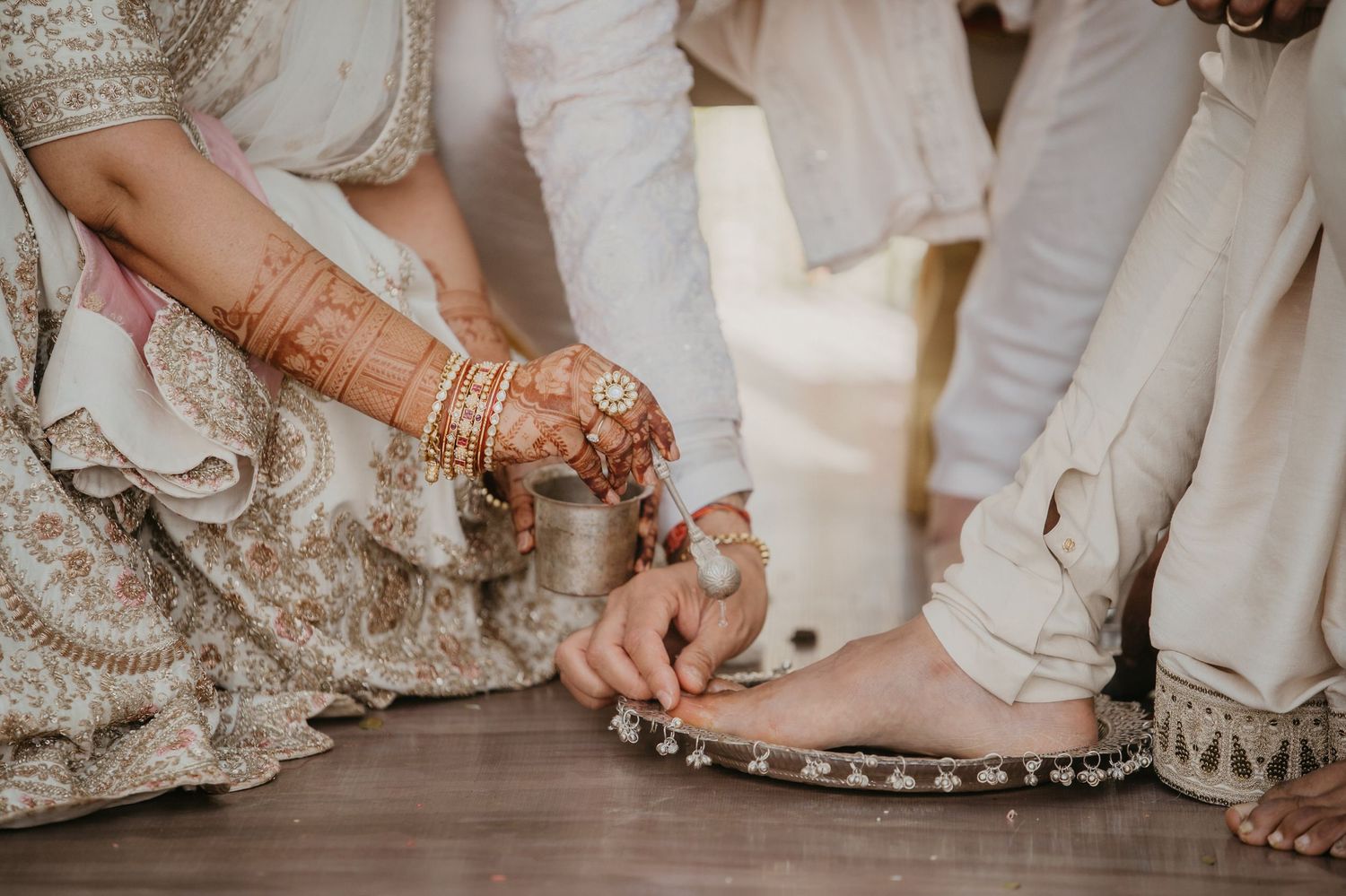 Detail shot of a bride's ornate henna-decorated hands against the backdrop of her traditional wedding dress.