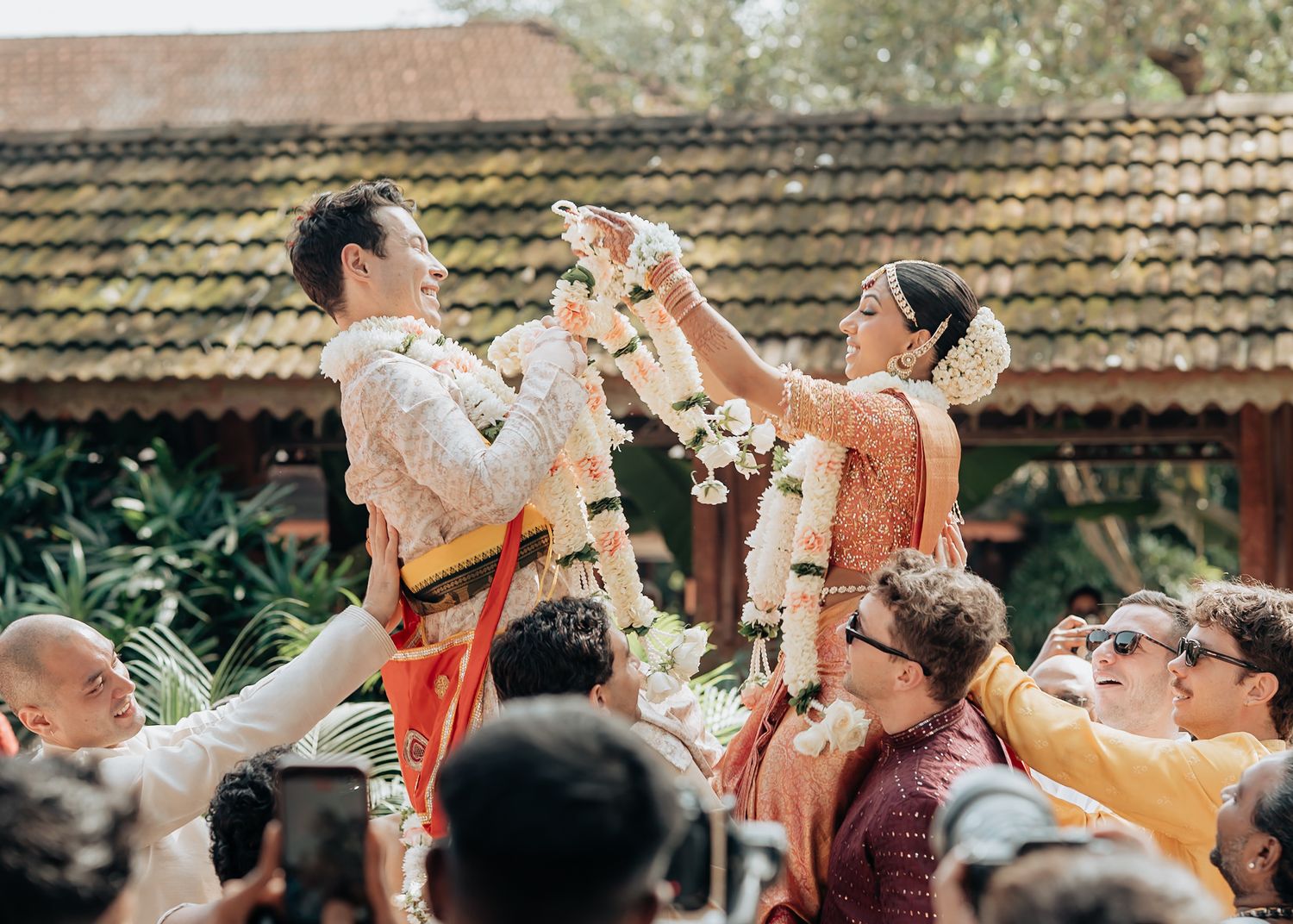 Indian bride and groom exchanging floral garlands during a traditional Hindu wedding ceremony outdoors.