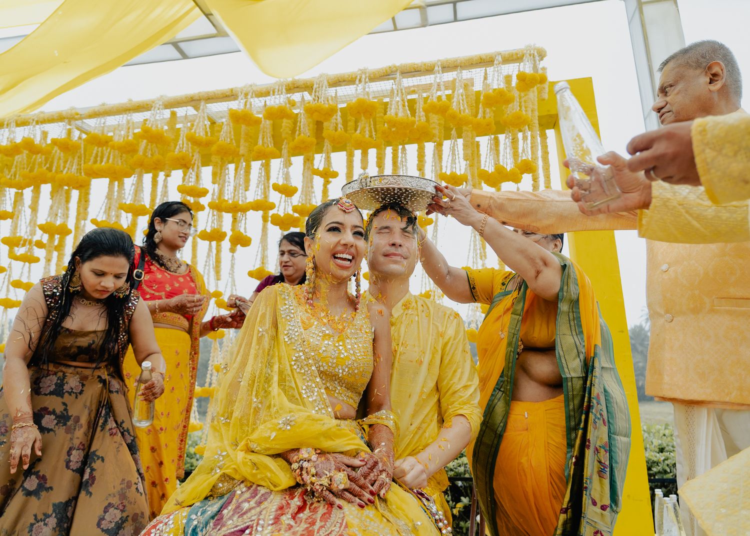 Wedding party gathering under yellow marigold flower decorations.