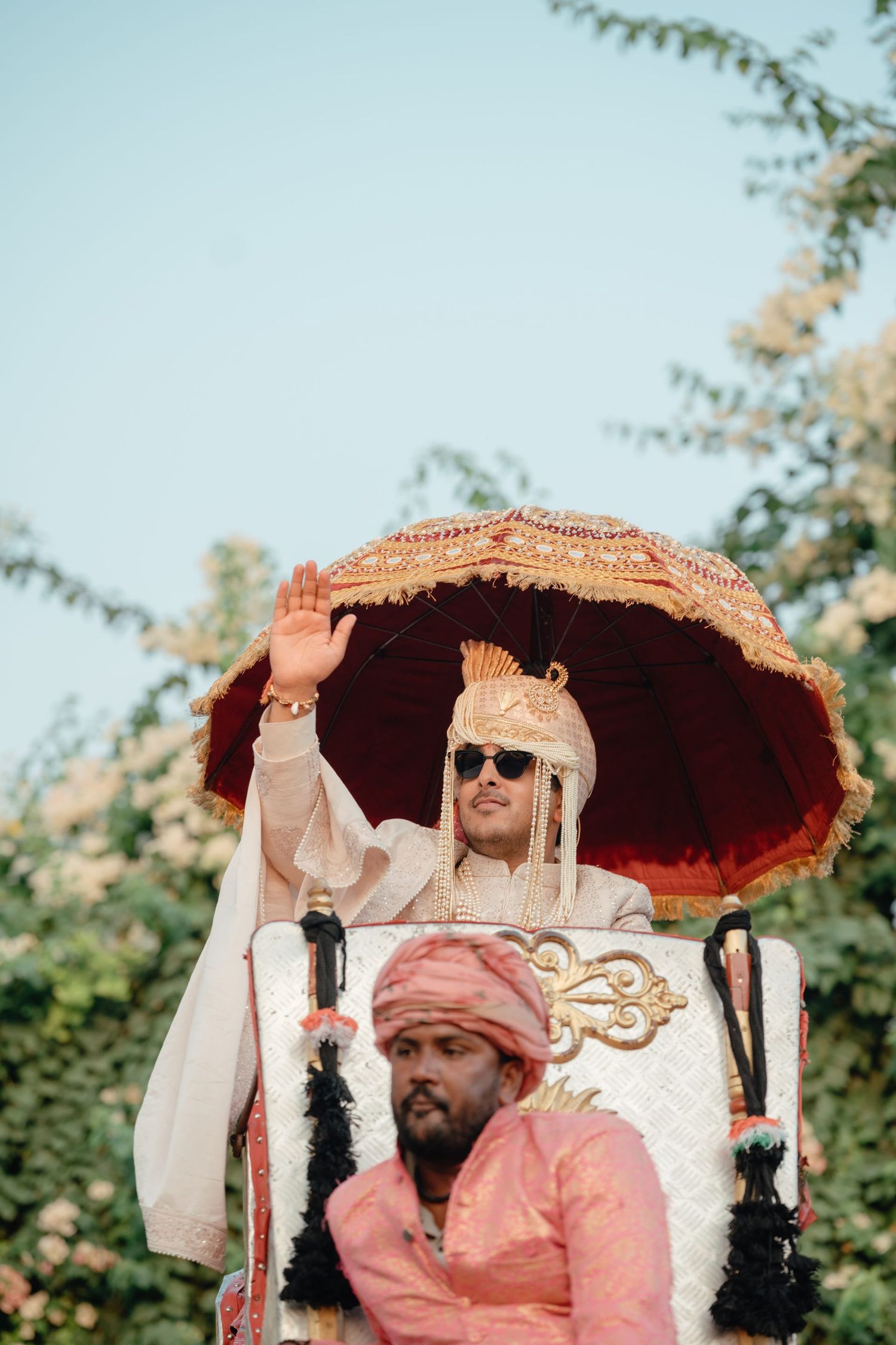 Decorated wedding palanquin carriers in pink and white traditional attire during ceremony.