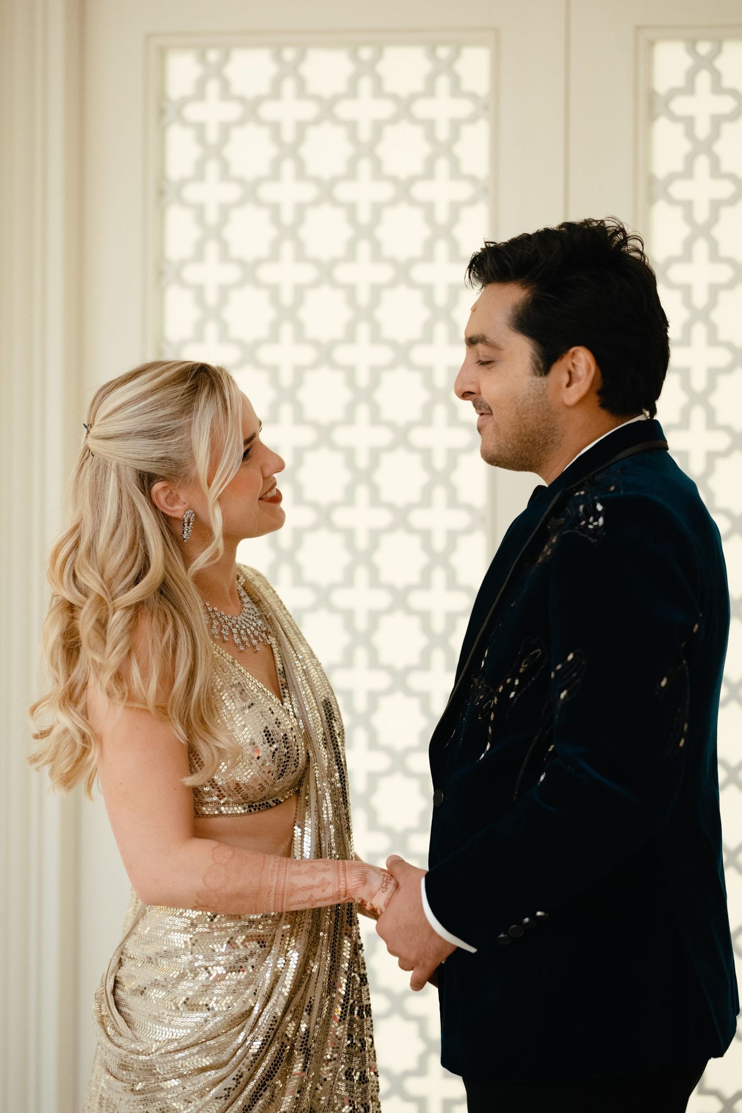 Formal couple sharing an intimate moment against white decorative wall panels.