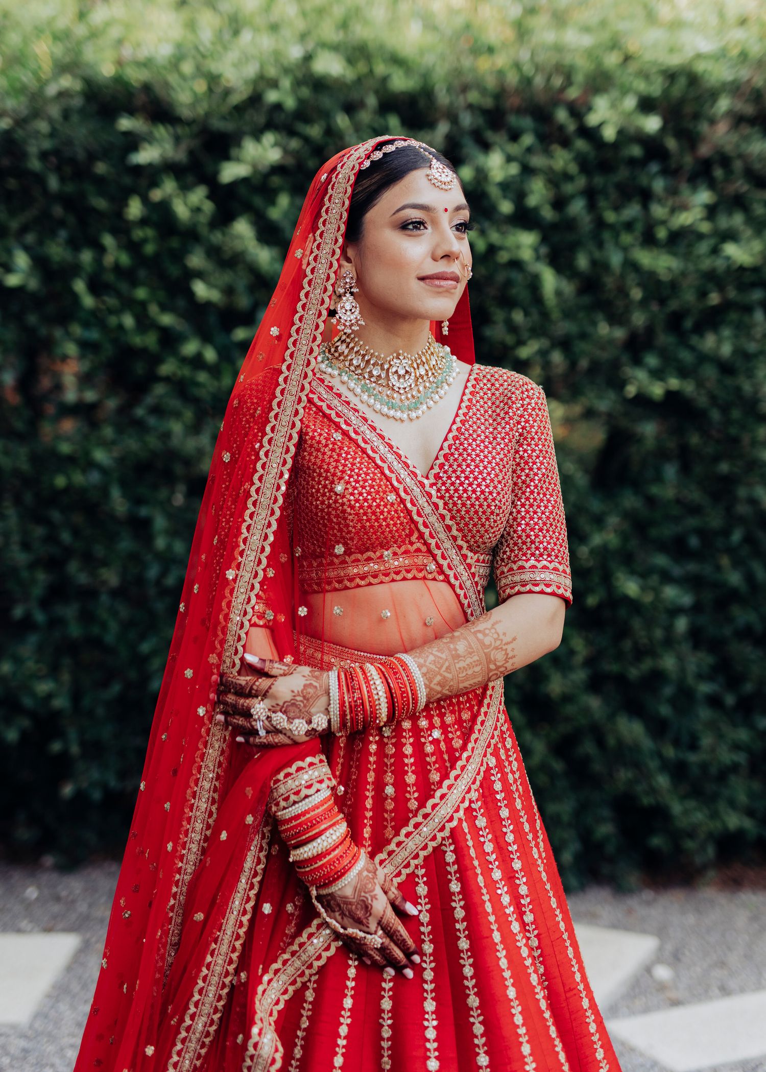 Beautiful traditional Indian bridal attire featuring an ornate red lehenga with gold embroidery and matching jewelry.