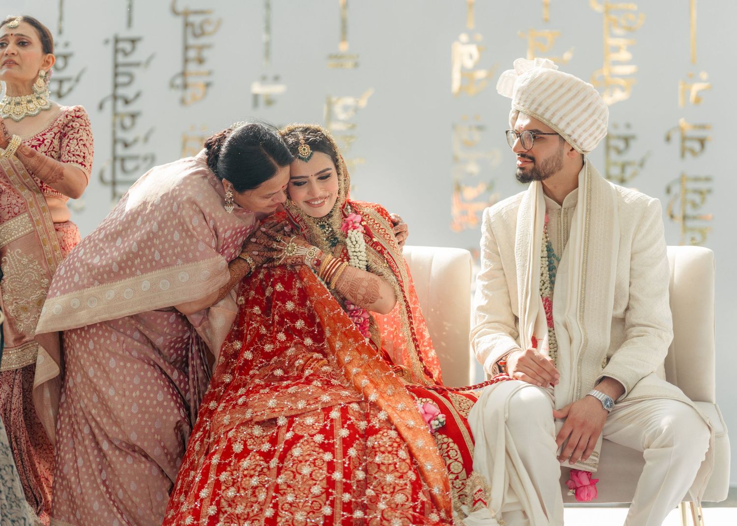 Traditional Indian wedding ceremony with bride in red lehenga and groom in white sherwani during intimate celebration moment.