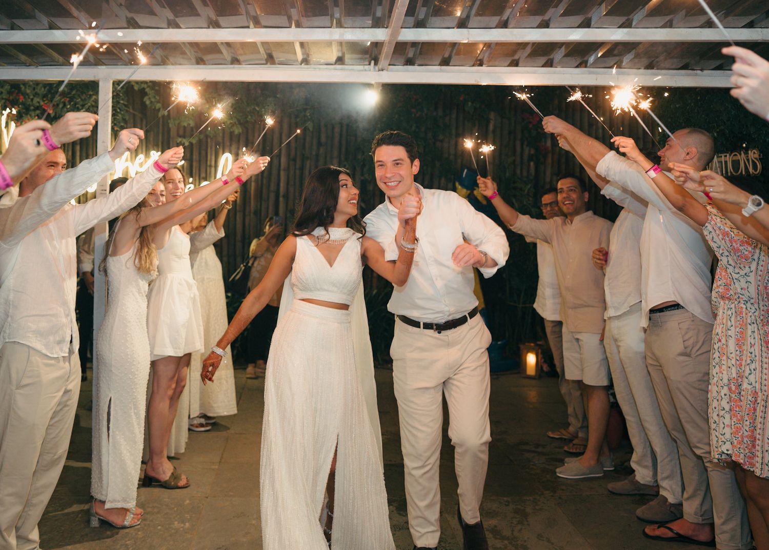 Wedding reception dance party with guests in white attire under string lights.