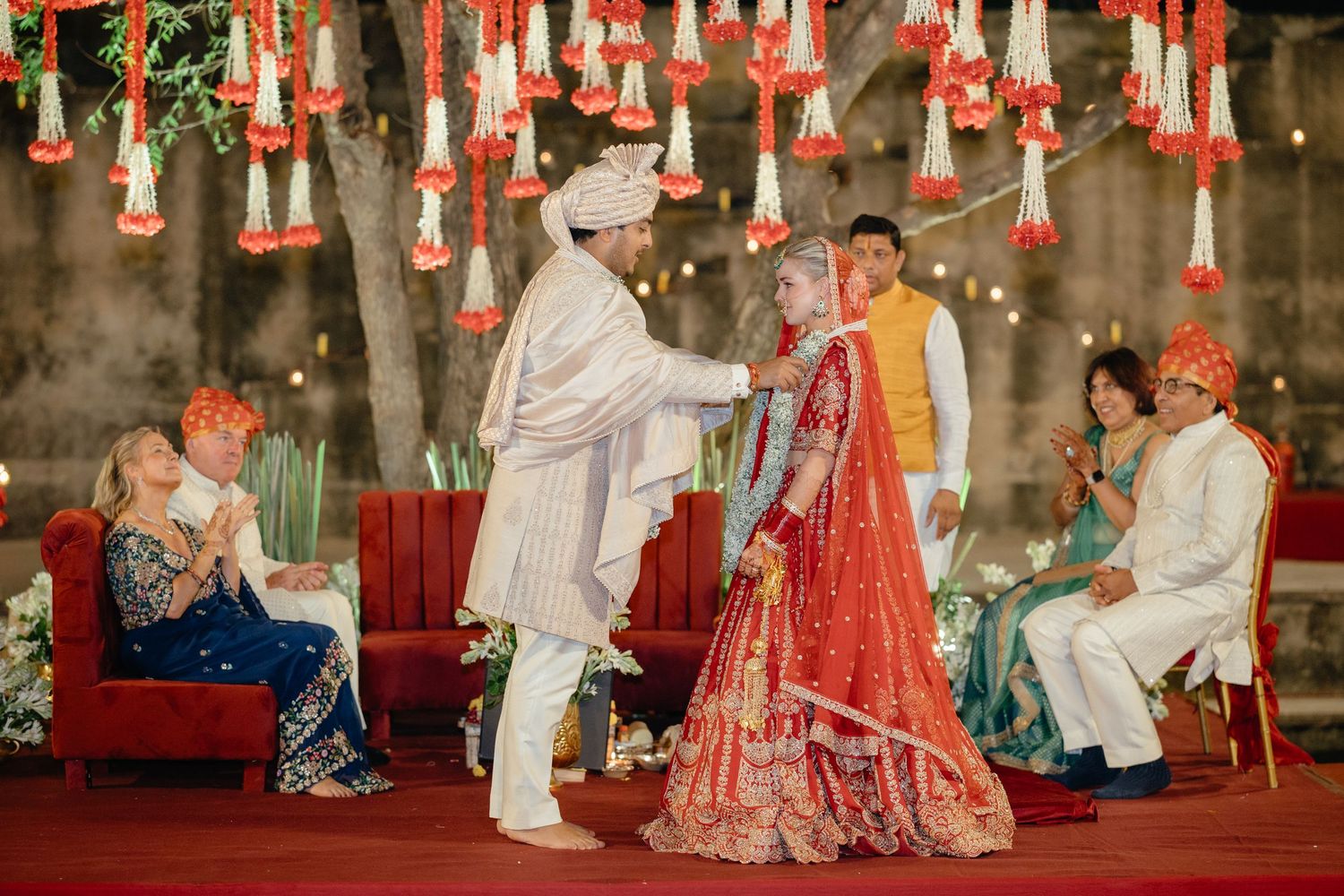 Wedding celebration with red and white hanging decorations creating magical ambiance.