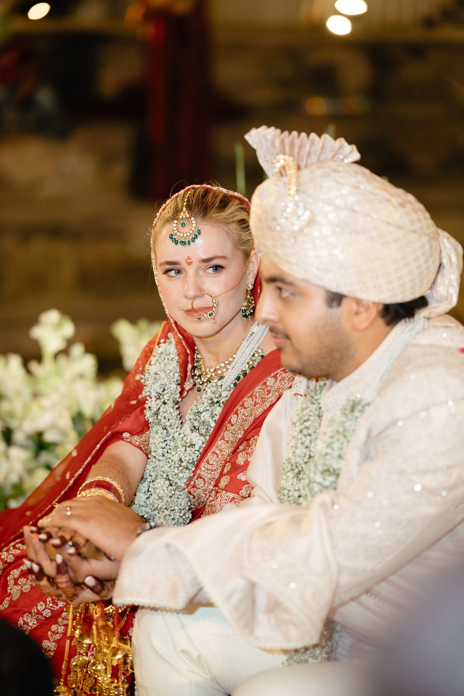 Close-up of couple in traditional Indian wedding attire with intricate jewelry and decorations.