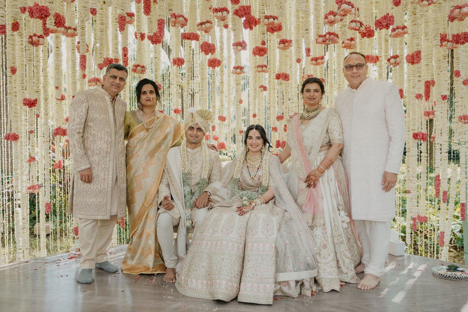 Romantic wedding scene with hanging red floral decorations and elegant white decor creating a dreamy atmosphere.